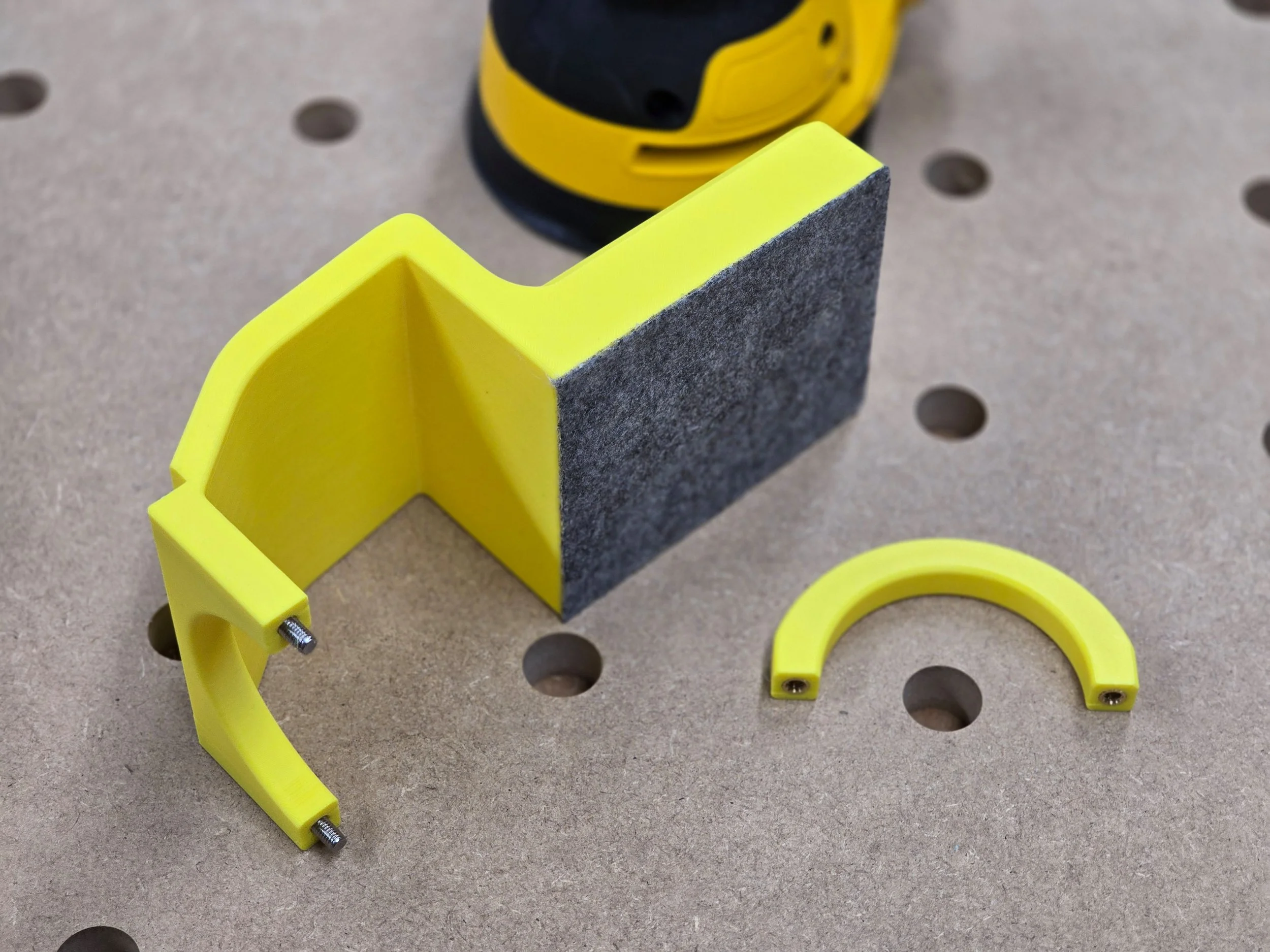 The edge guide disassembled, showing the main body with its felt contact pad, mounting screws, and a curved bracket piece