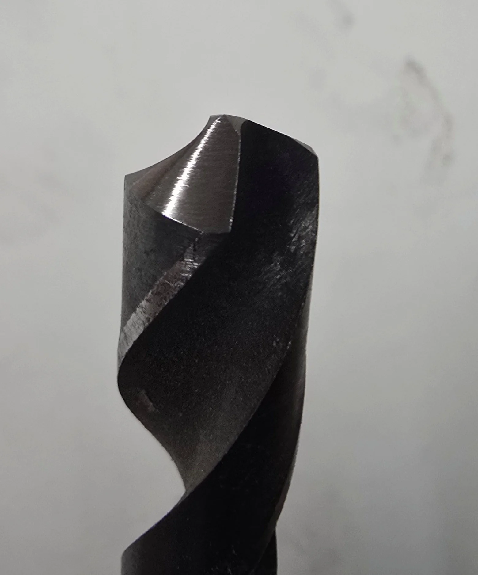 Close-up of a drill bit's freshly sharpened tip, showing the two ground cutting-edge facets