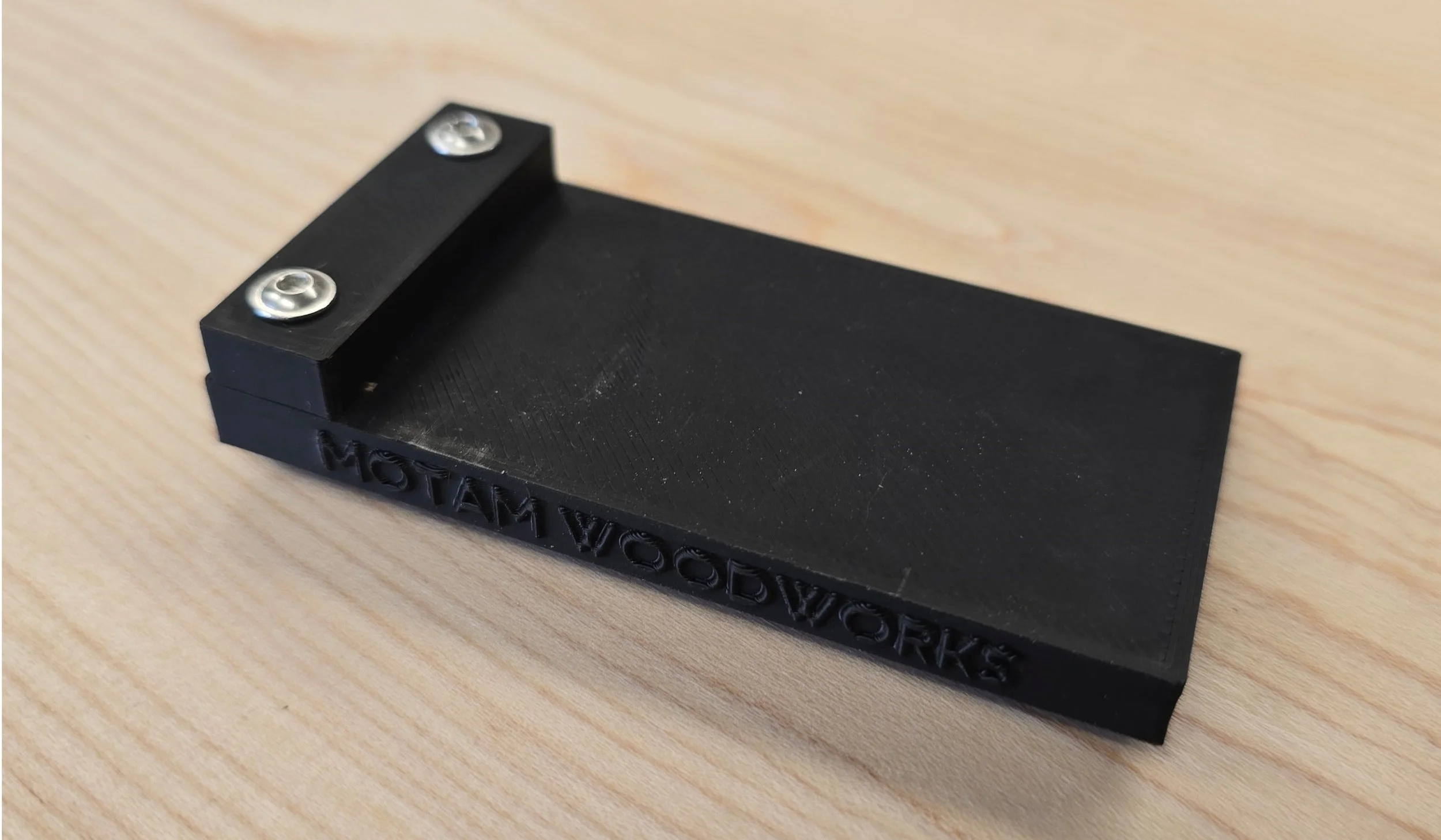 The Motam square guide jig on its own on a wooden bench, showing the "Motam Woodworks" branding along its edge