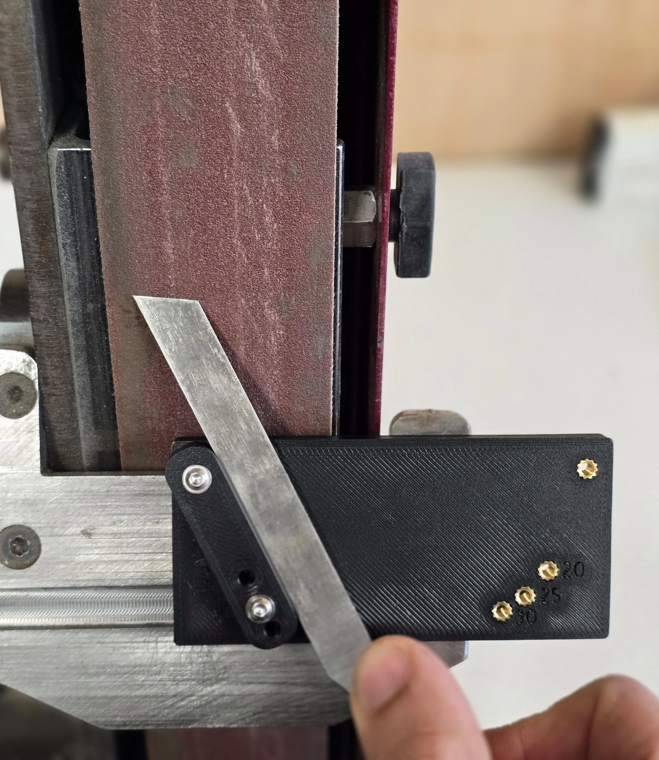 Skew chisel being sharpened on Robery Sorby ProEdge belt sander, using Motam Woodworks skew chisel jig set to one of its 20/25/30 degree positions