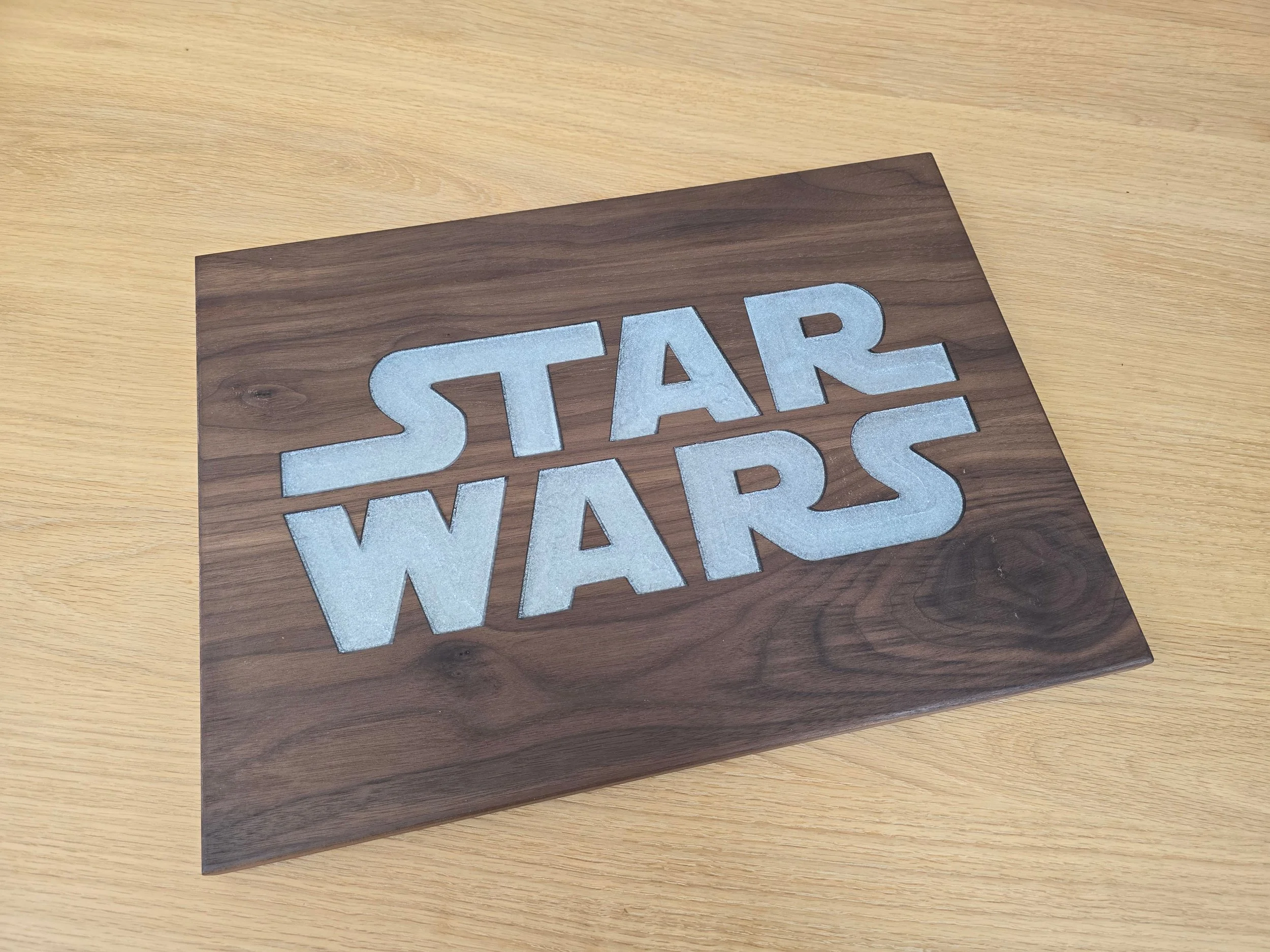 Black walnut serving board with the Star Wars logo inlaid in white resin, angled view