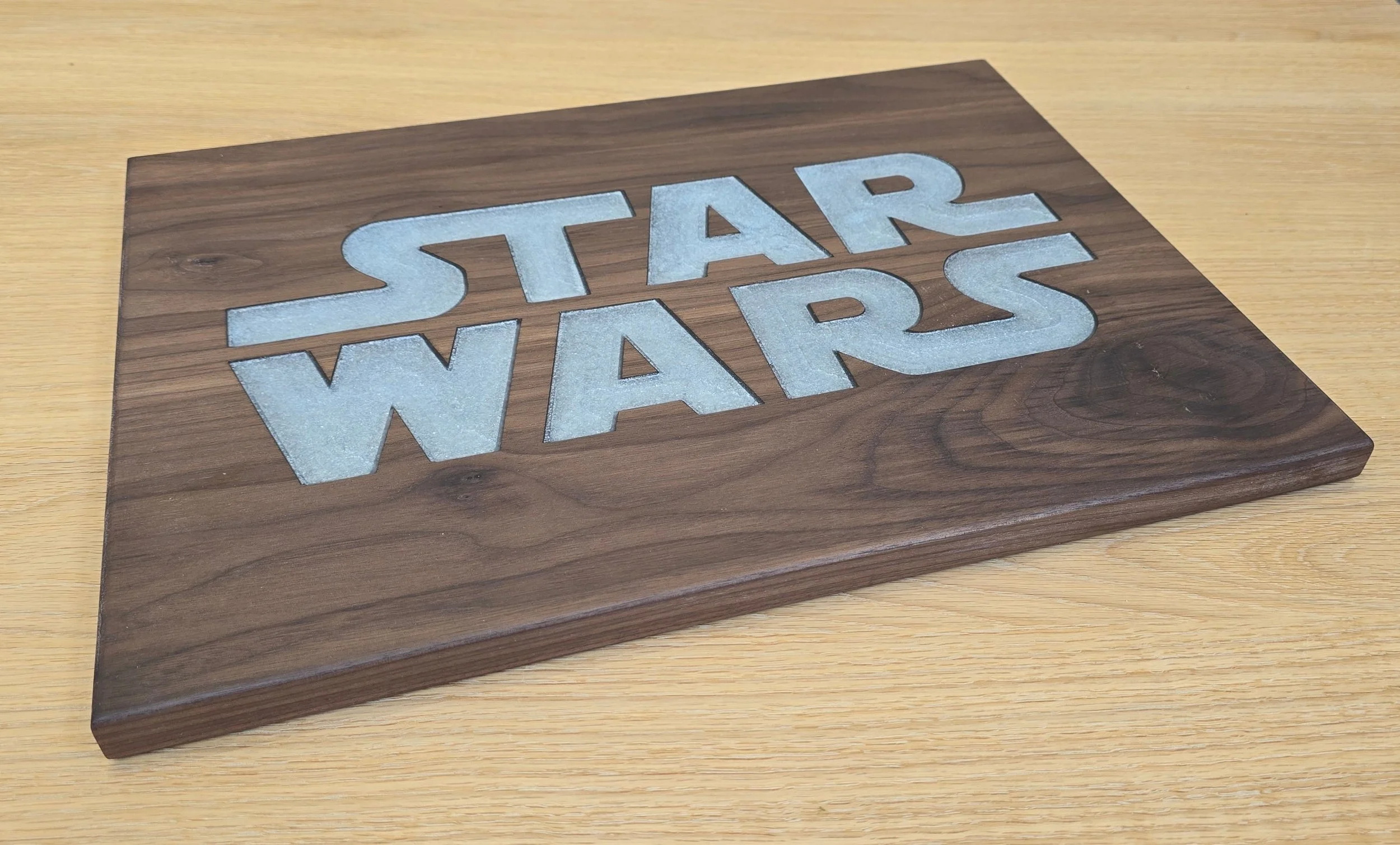 Black walnut serving board with the Star Wars logo inlaid in white resin, straight-on view