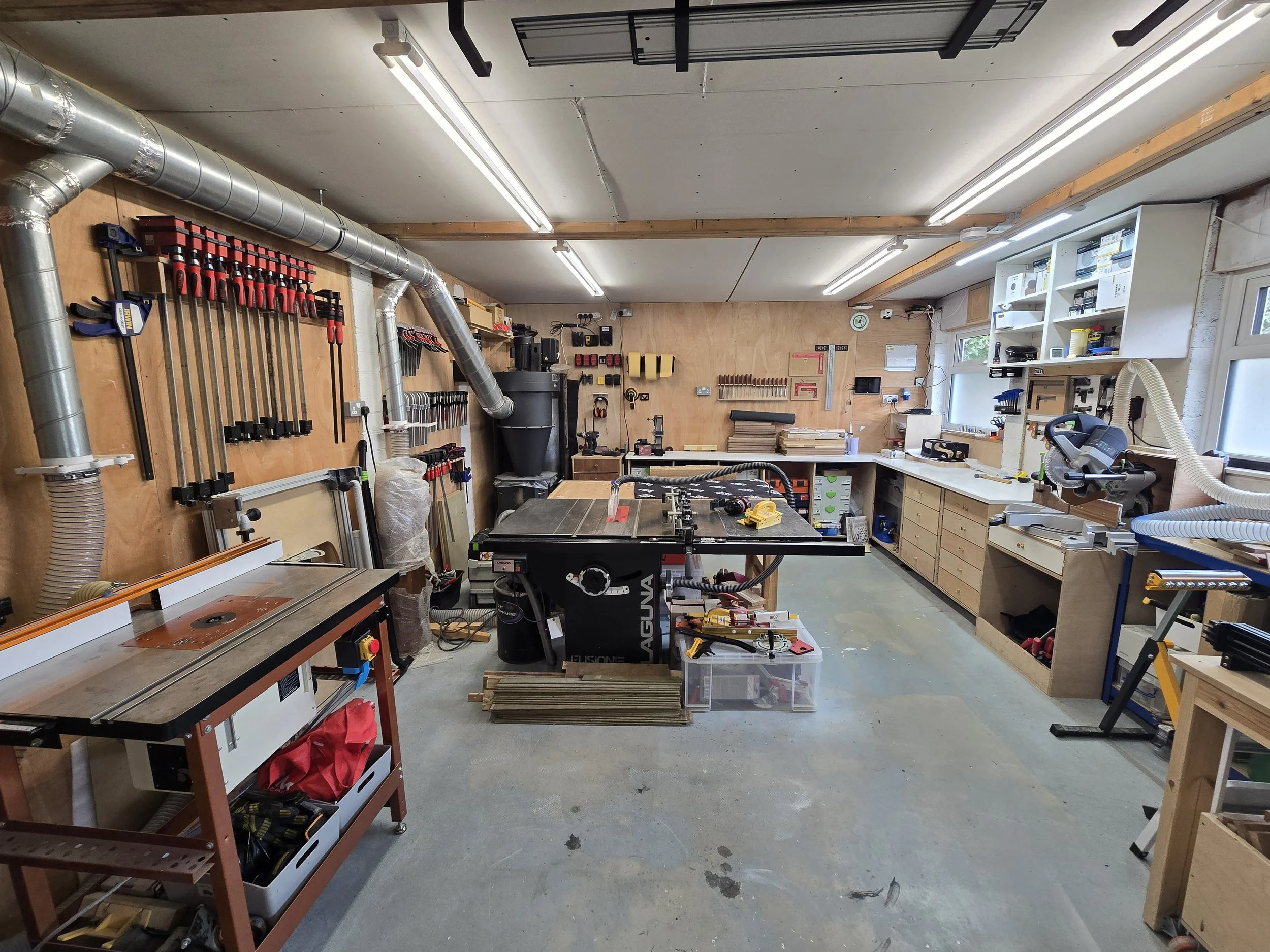 A woodworking workshop with tools, workbenches, storage shelves, and equipment.