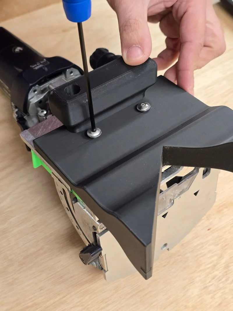 Person tightening screws on a mechanical or electronic device using a screwdriver.