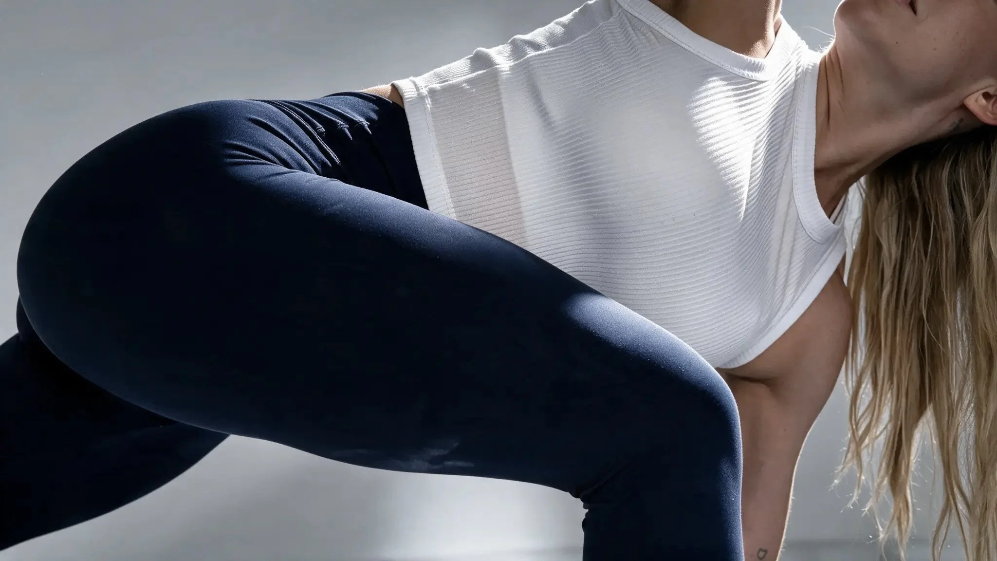 Nahaufnahme von fitnessübungen mit einer Frau in weißen Oberteilen und schwarzen Leggings, die im Freien trainiert.