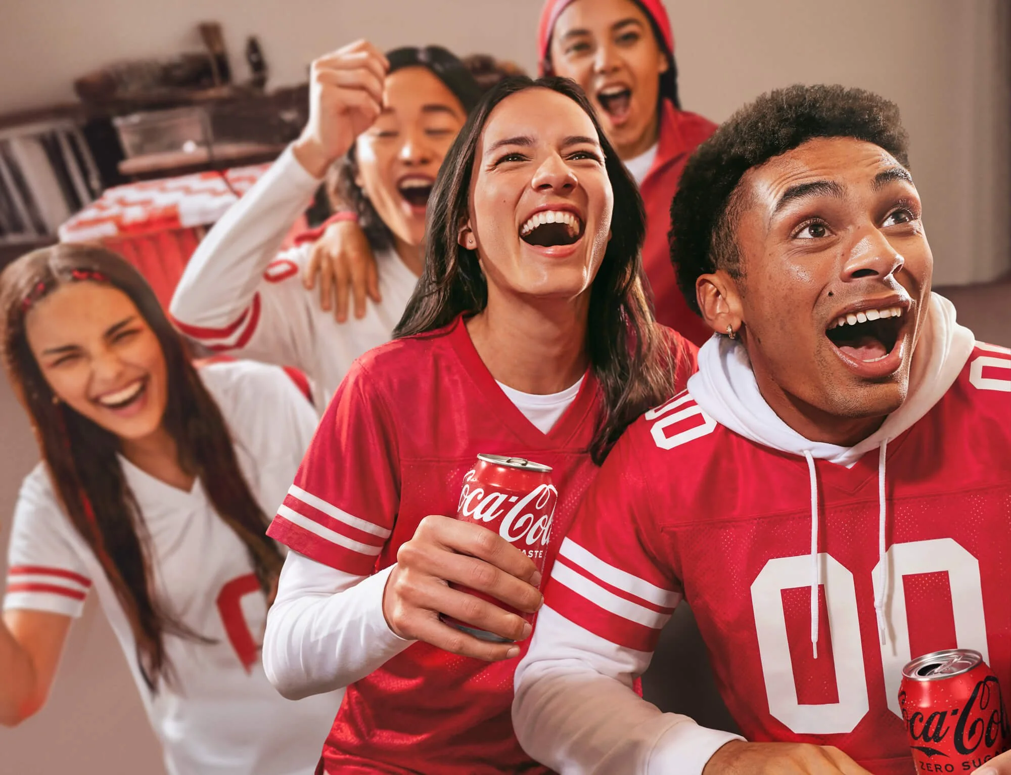Group of friends wearing red and white sports jerseys celebrating and having fun at a party, holding soda cans.