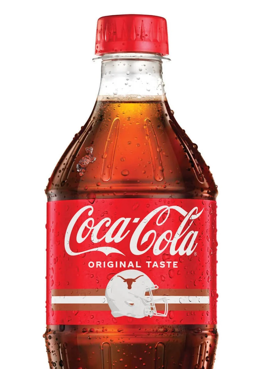A Coca-Cola bottle with a red cap, labeled 'Coca-Cola Original Taste,' featuring a logo of a longhorn steer helmet on the front.