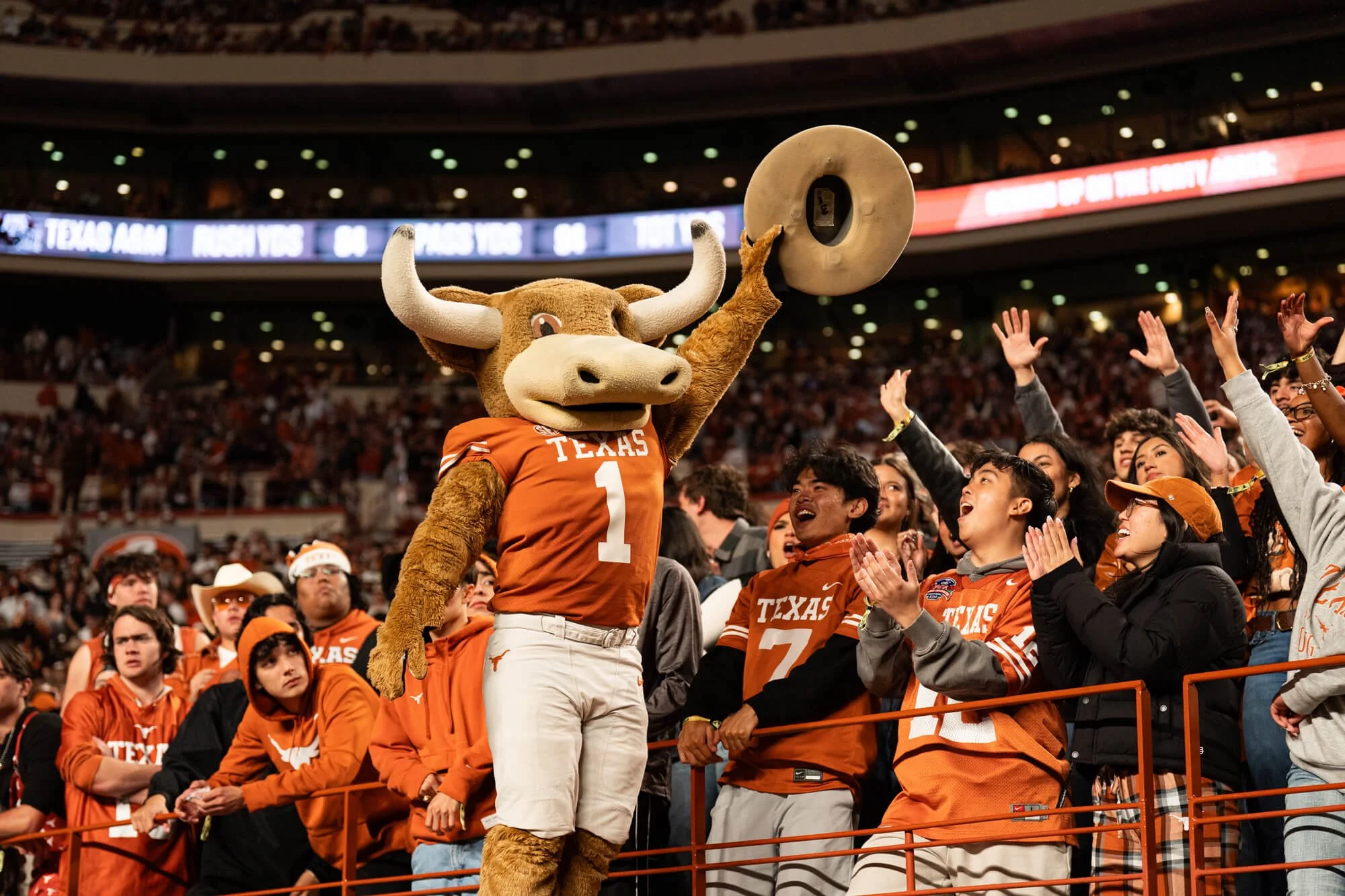 University of Texas football game with a football mascot and cheering crowd in orange uniforms.