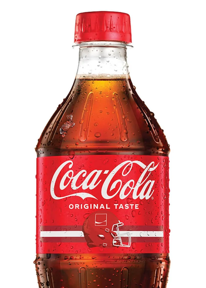 A plastic Coca-Cola bottle with a red cap, filled with dark caramel-colored soda, covered in condensation droplets, and labeled 'Coca-Cola Original Taste.'