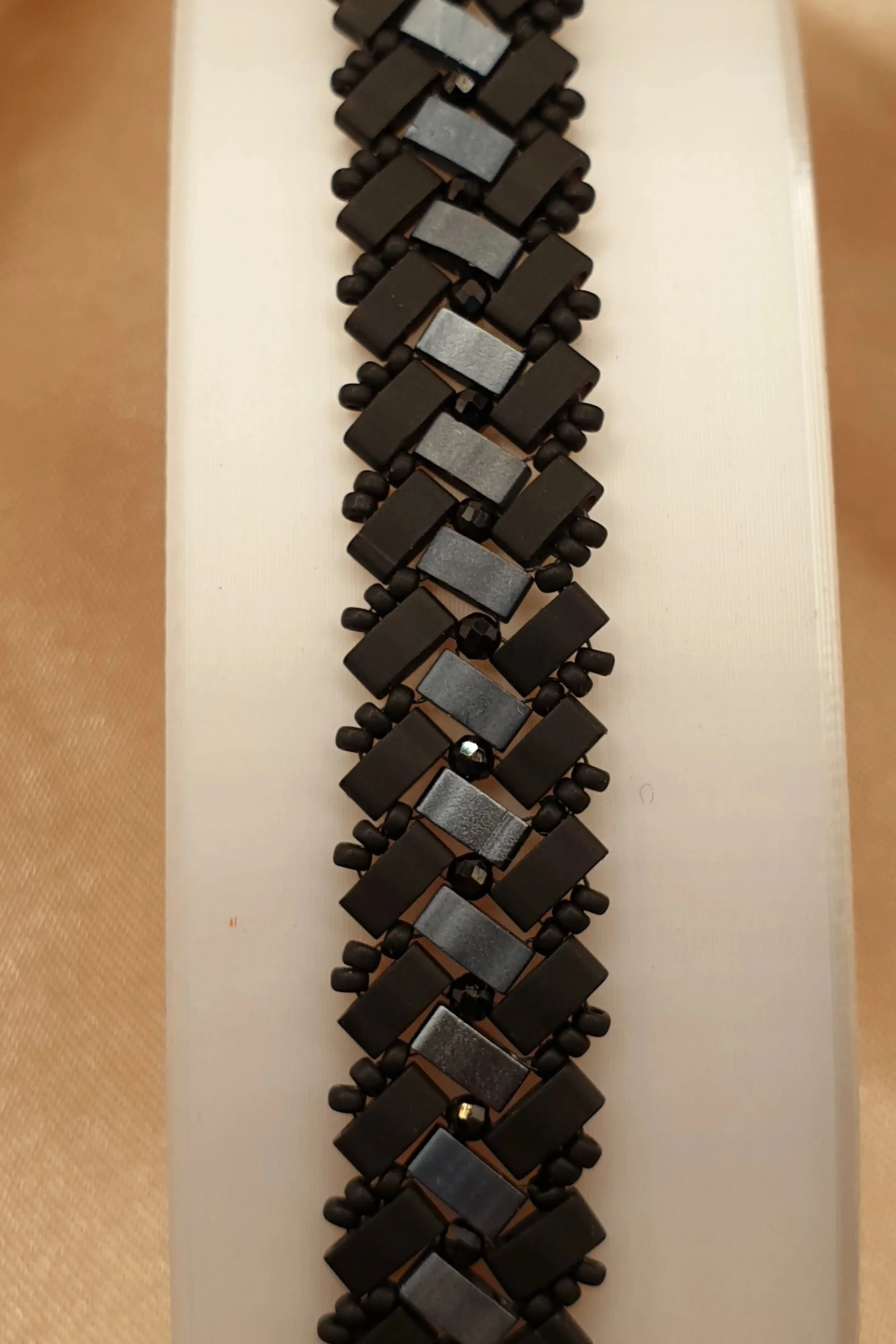 Gros plan du tissage géométrique noir mat, gris métallisé et onyx du bracelet Éclipse d’Onyx