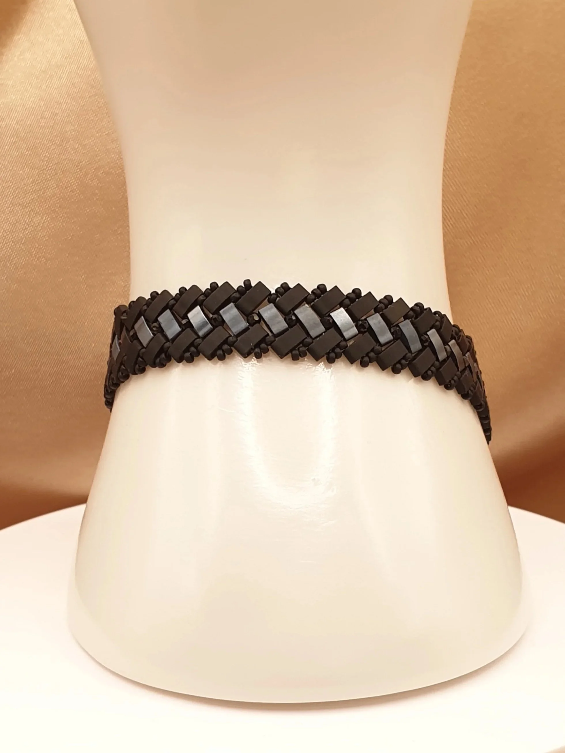 Bracelet Éclipse d’Onyx autour d’un présentoir blanc, vue de face du tissage