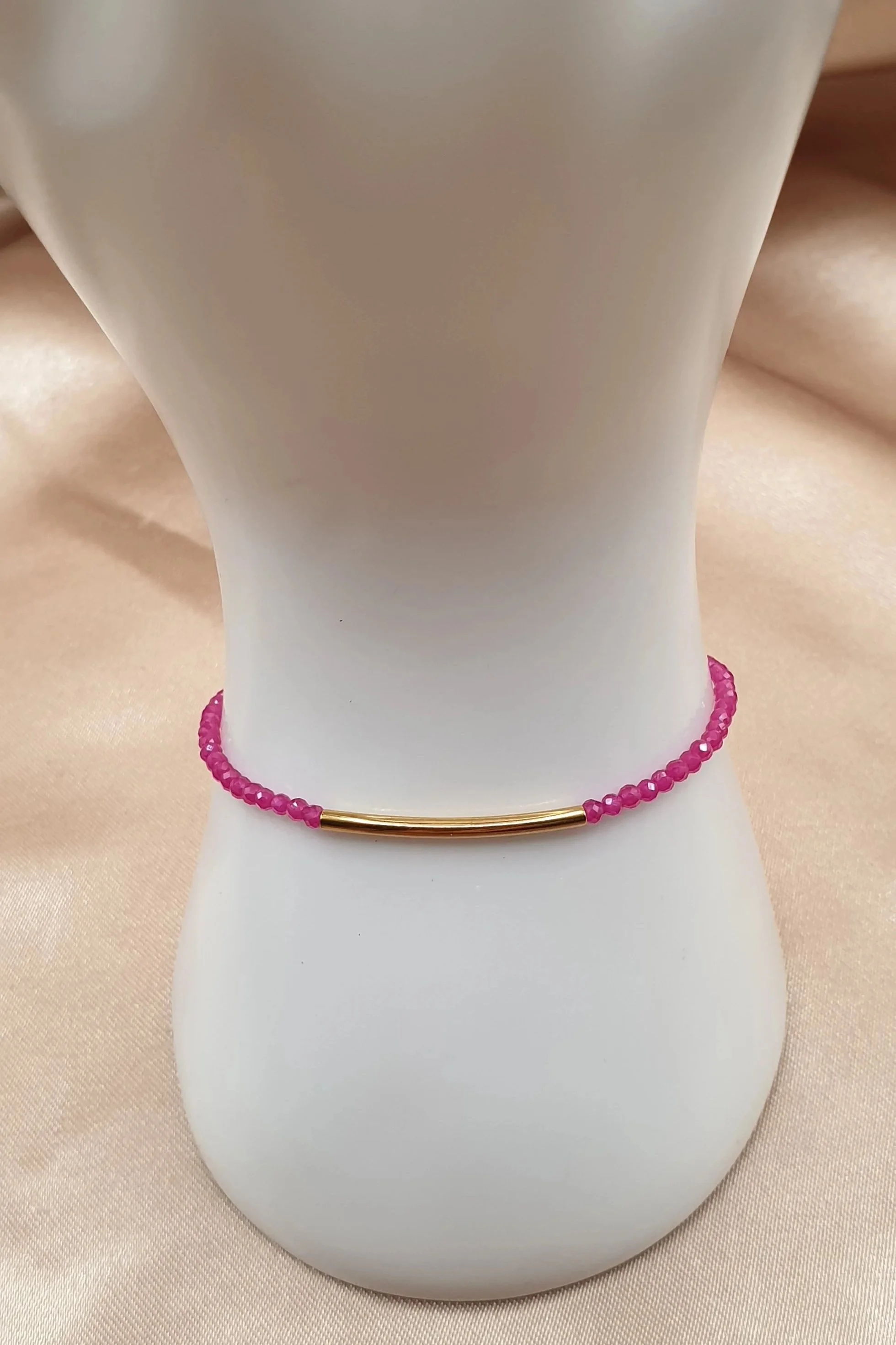 Bracelet Fil de Rubis présenté de face sur un support blanc, avec son élément central doré