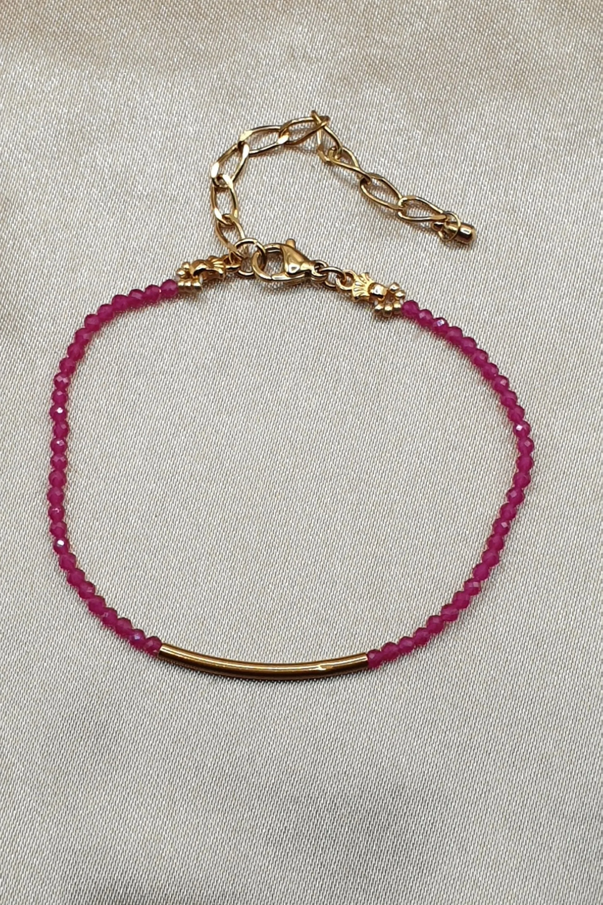 Bracelet Fil de Rubis posé à plat, perles roses facettées, tube doré et fermoir visibles