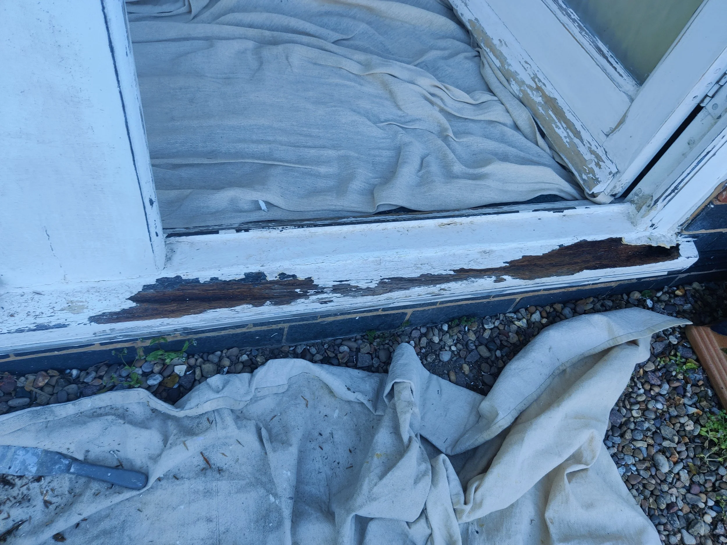 A weathered painted wooden window frame with chipped paint and visible rot.