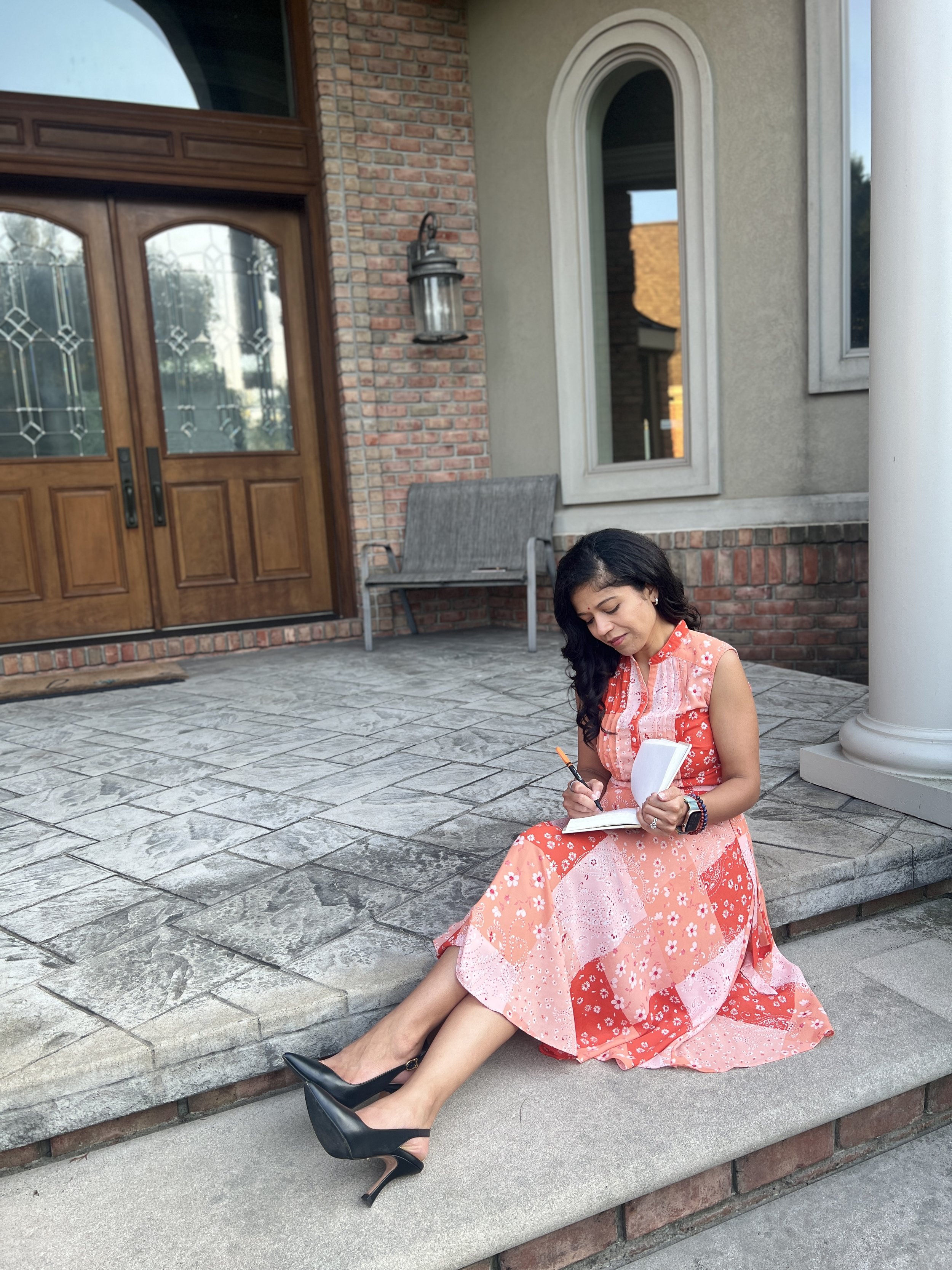 Nishi Jani Rajguru sitting outside and writing in her notebook.
