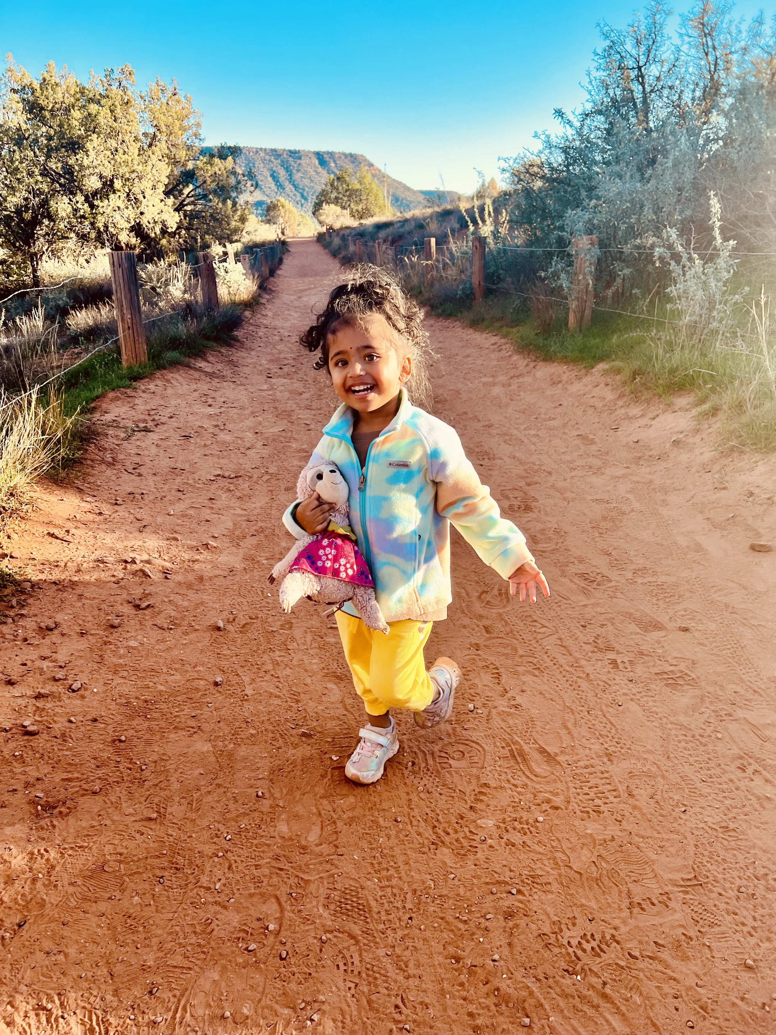 Nishi's daughter running on a path with red sand in Sedona.
