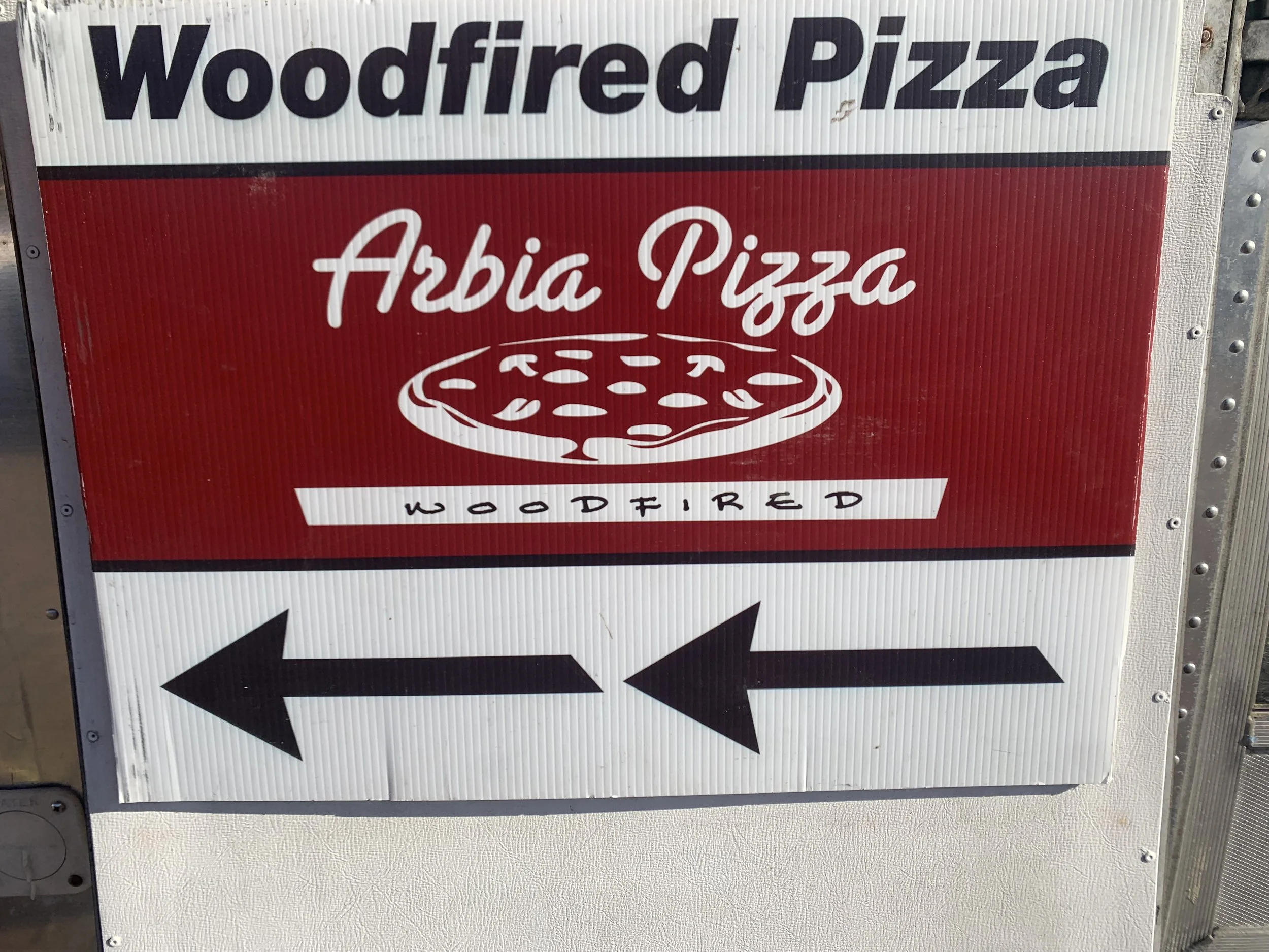 Sign for Wood-fired Pizza and Arbia Pizza with arrows pointing left and right.