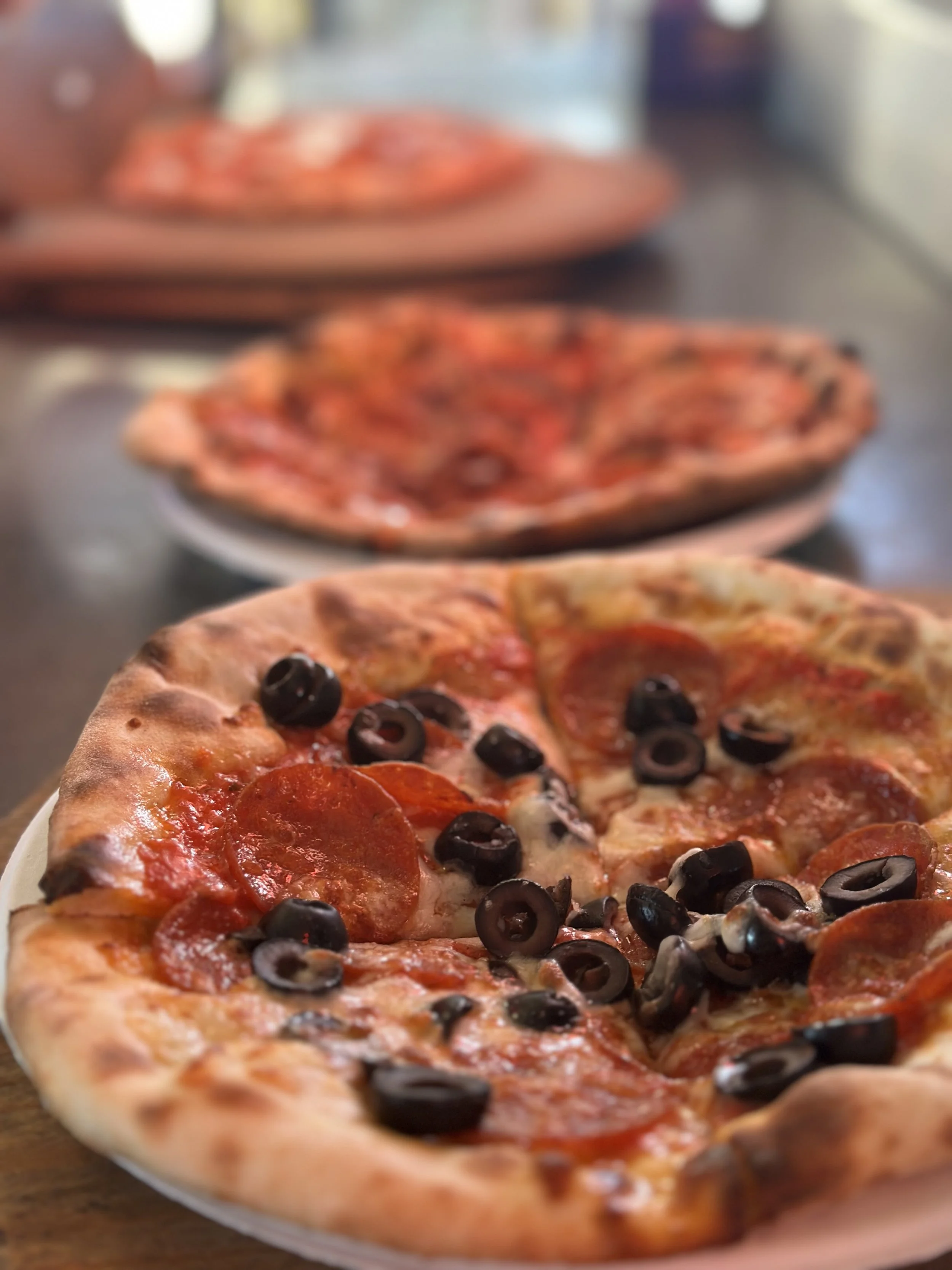 Close-up of a pepperoni and black olive pizza on a white plate.