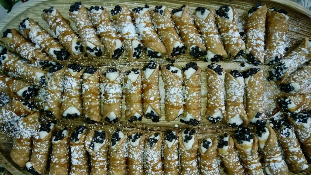A large tray filled with Belgian waffles topped with whipped cream and chocolate chips, dusted with powdered sugar.