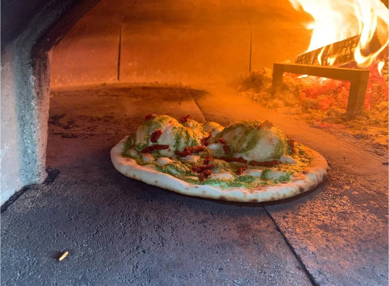 Pizza baking inside a pizza oven with flames and heating elements visible