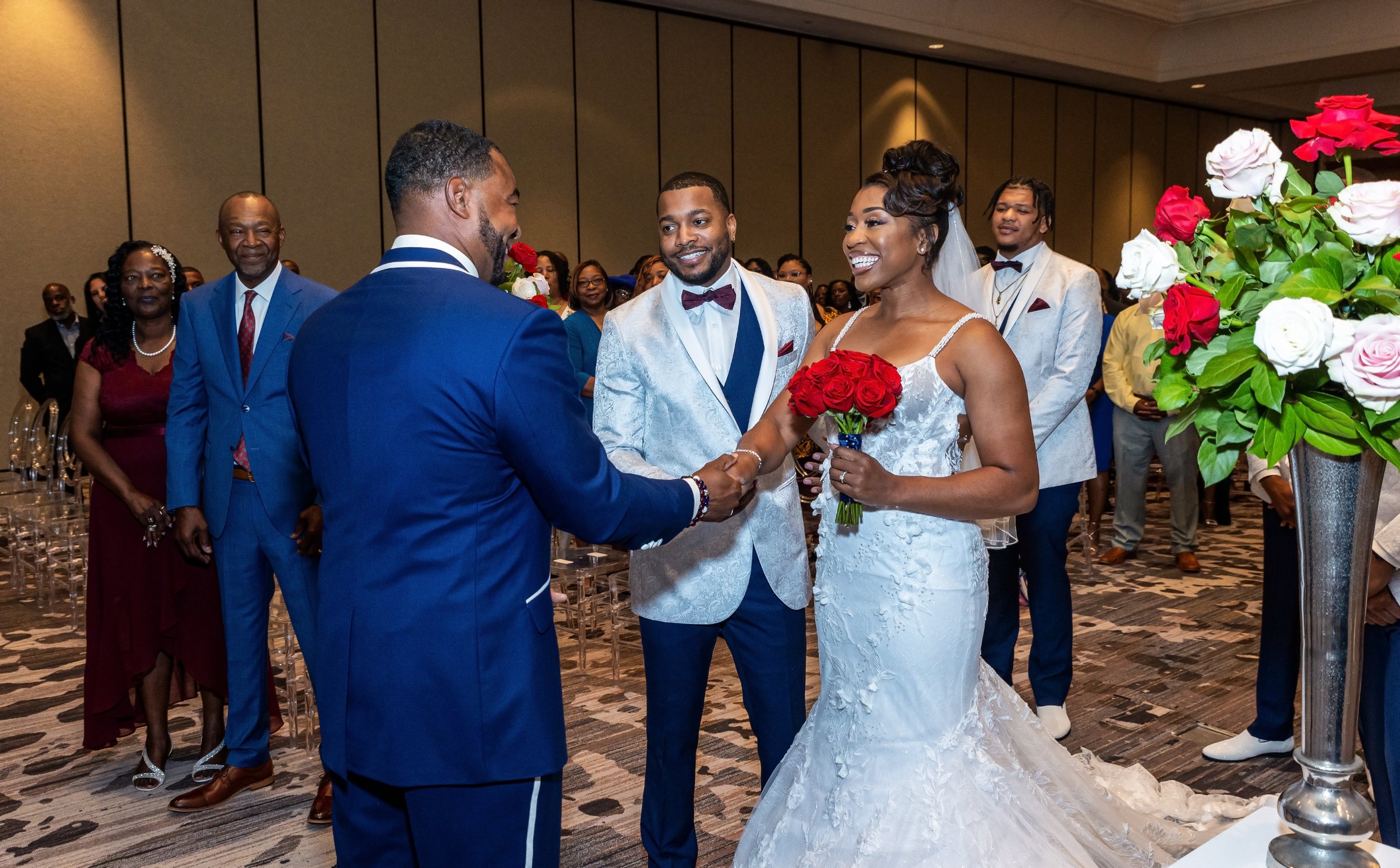 A wedding ceremony with a bride and groom exchanging vows, surrounded by guests, with flowers and decorations in the background.