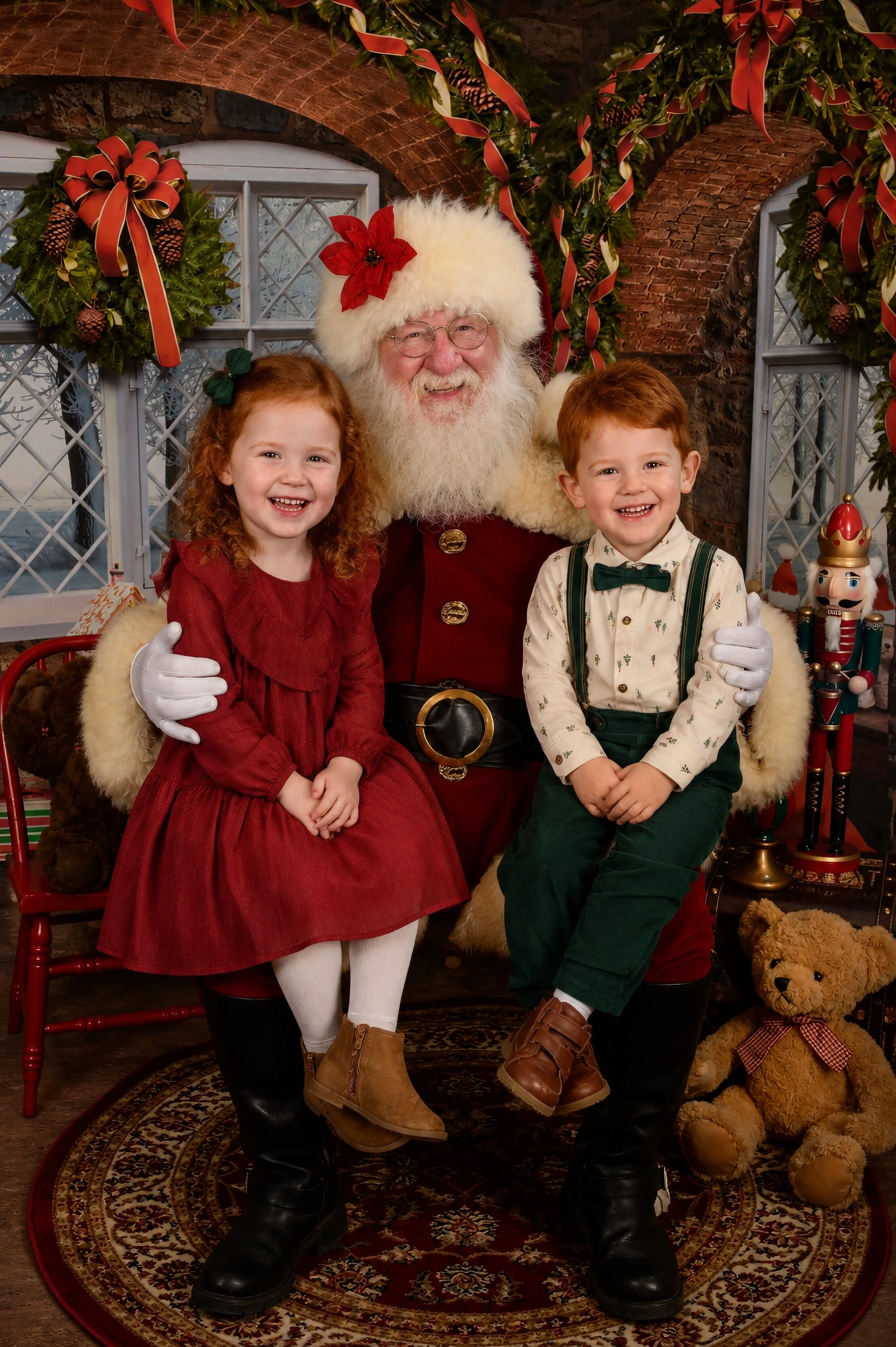 A festive holiday scene with Santa Claus sitting with two children, a girl in a red dress and a boy in a white shirt with holiday prints. They are all smiling and sitting on Santa's lap, with Christmas decorations including wreaths, ribbons, and nutc