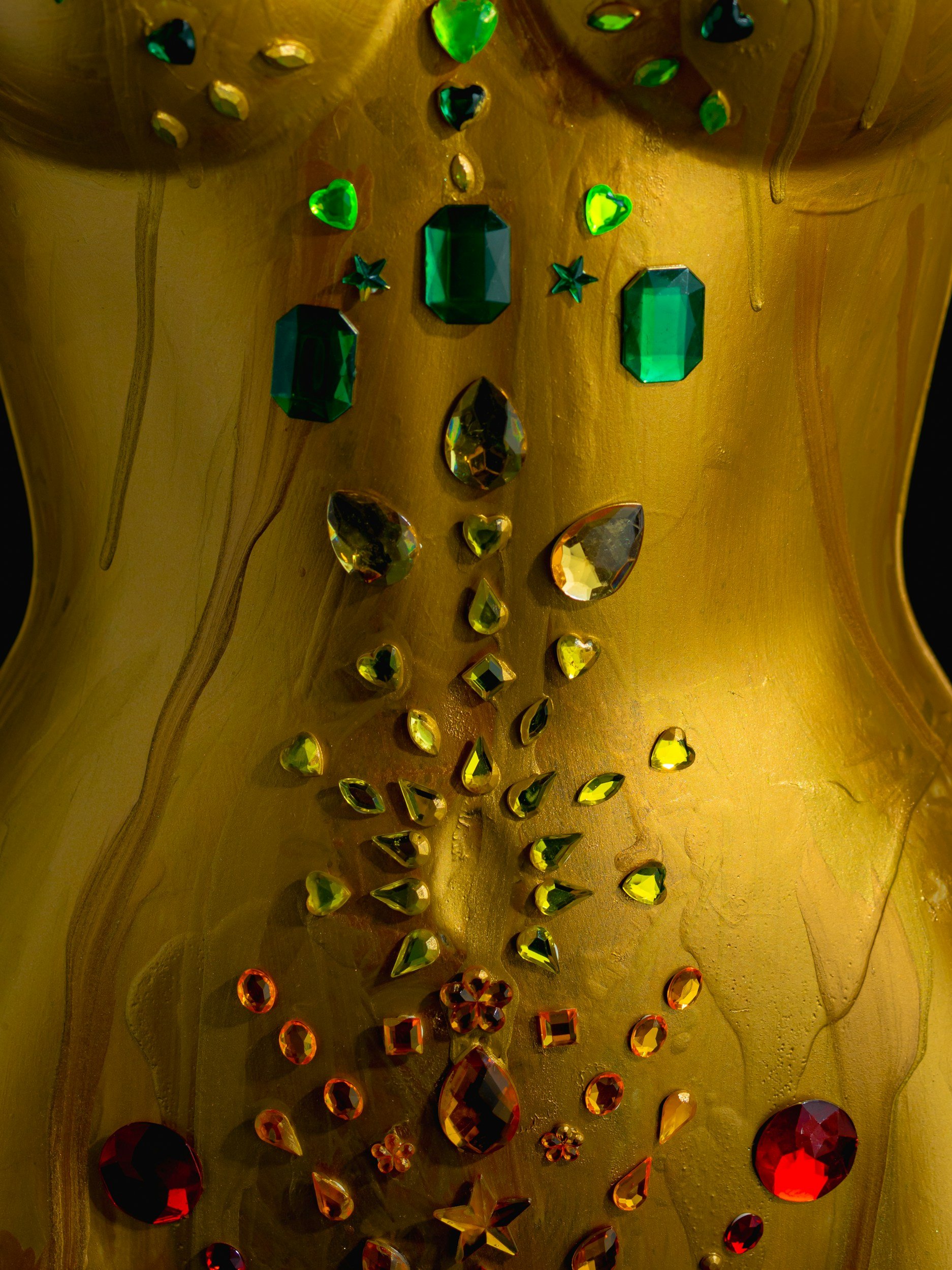 Golden sculpted torso adorned with emerald and red gemstones along the body's energy centers