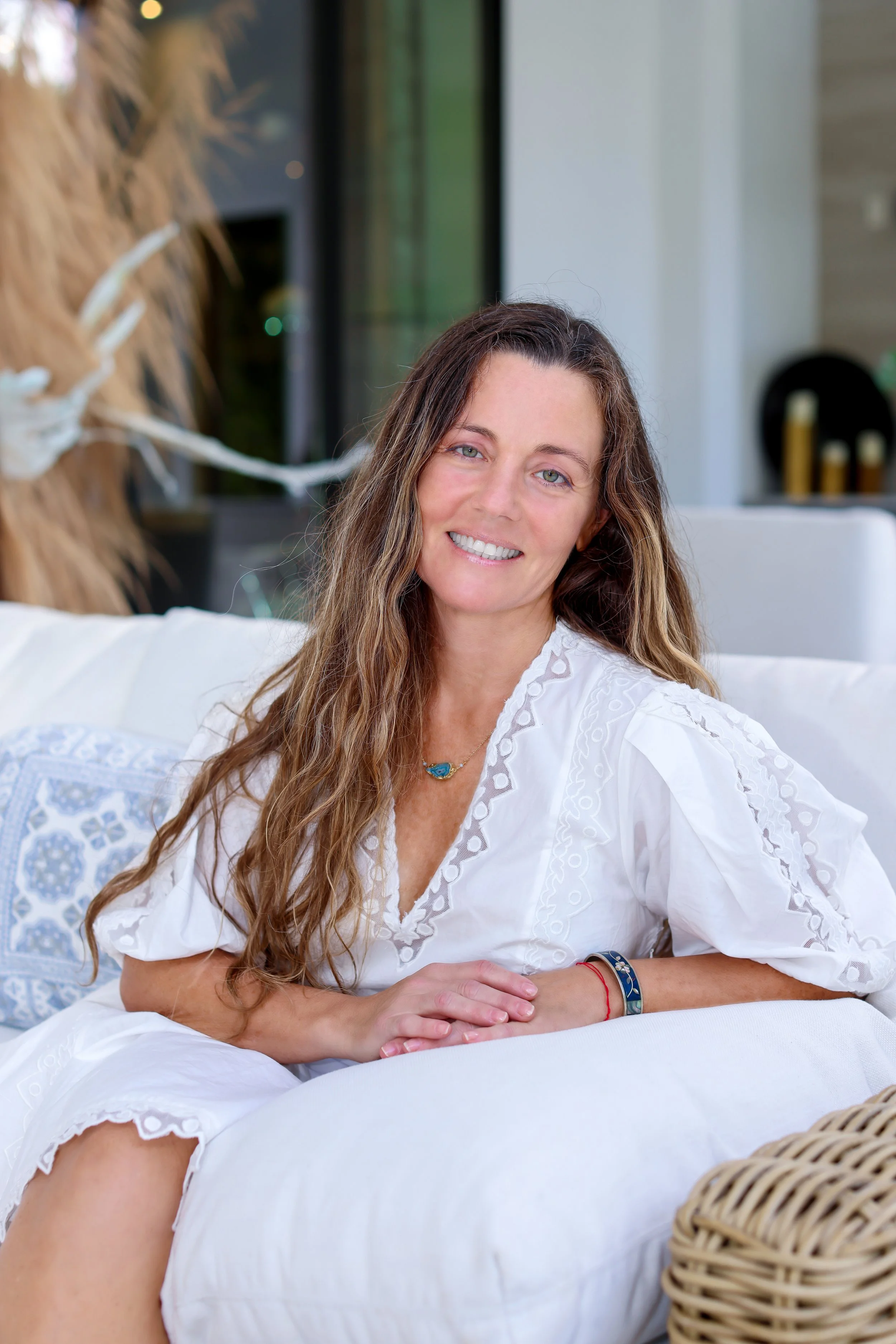 Dr. Dawn Murrin, licensed acupuncturist, smiling on a white sofa