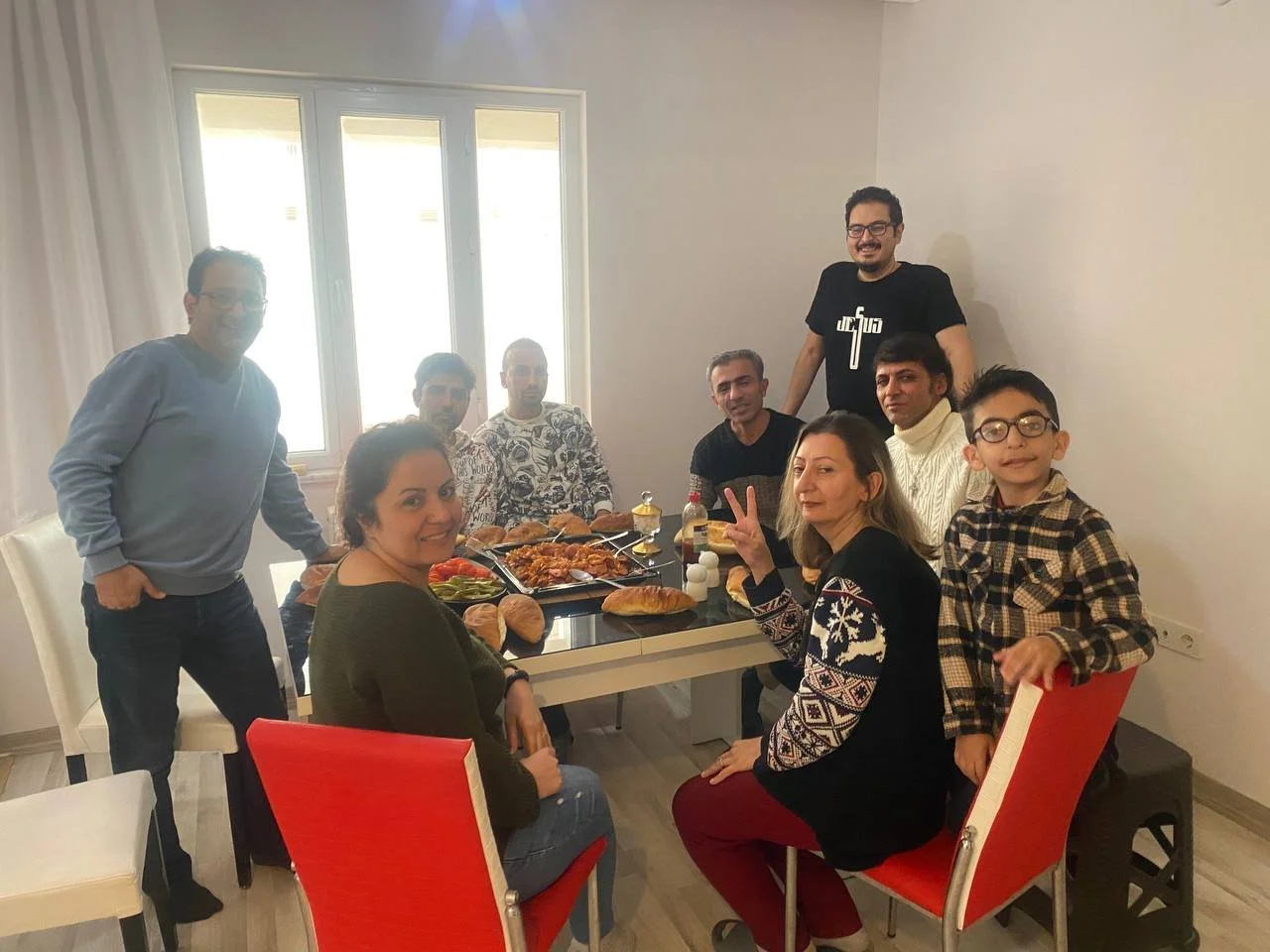 Adults and a child gather around a dining table filled with food inside an apartment in Kırıkkale, Türkiye.