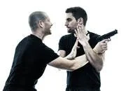 A confrontation between two men, one holding a gun pointed at the other.