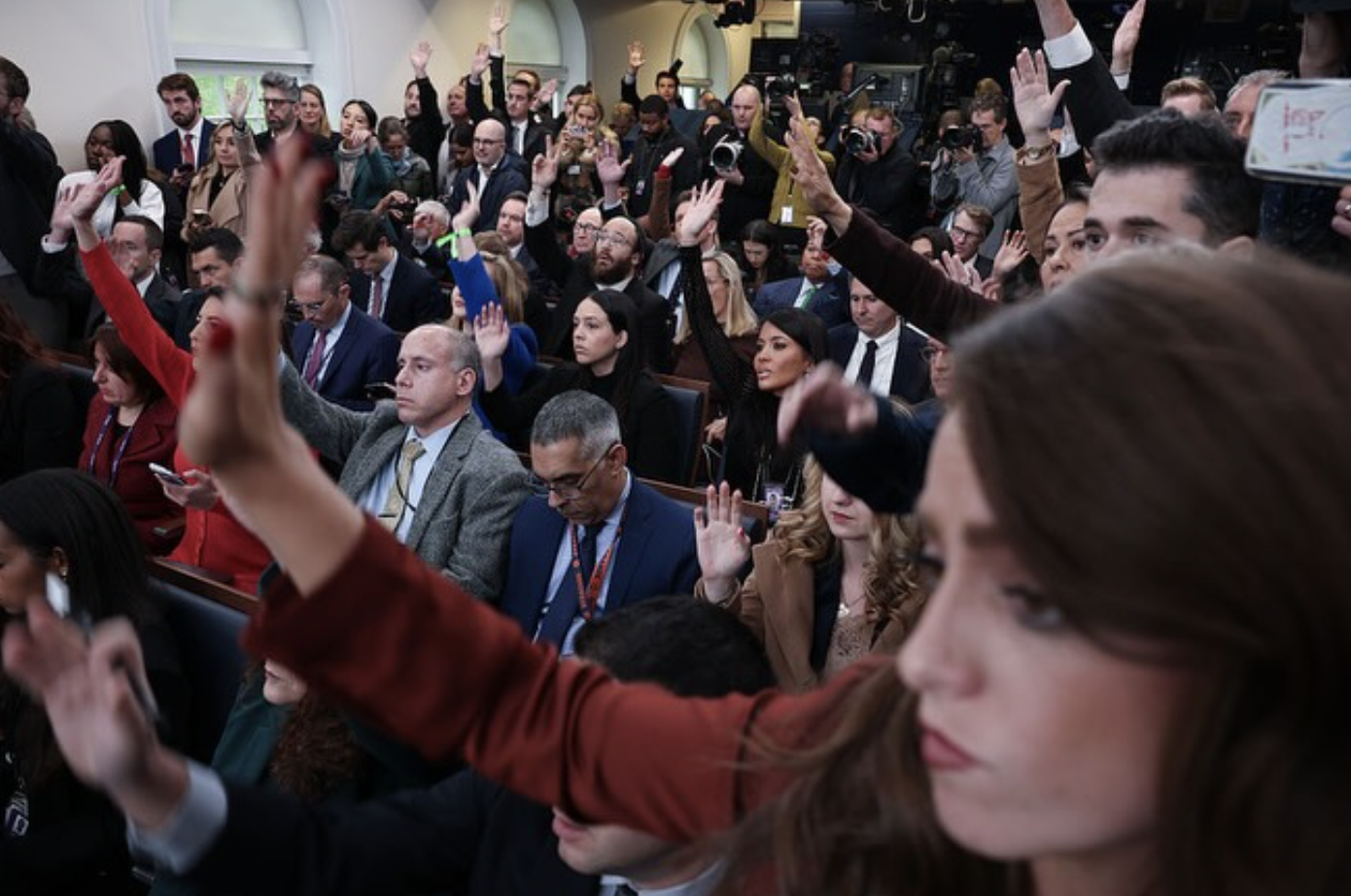 Reporters raise their hands in the James Brady Briefing Room at the White House.