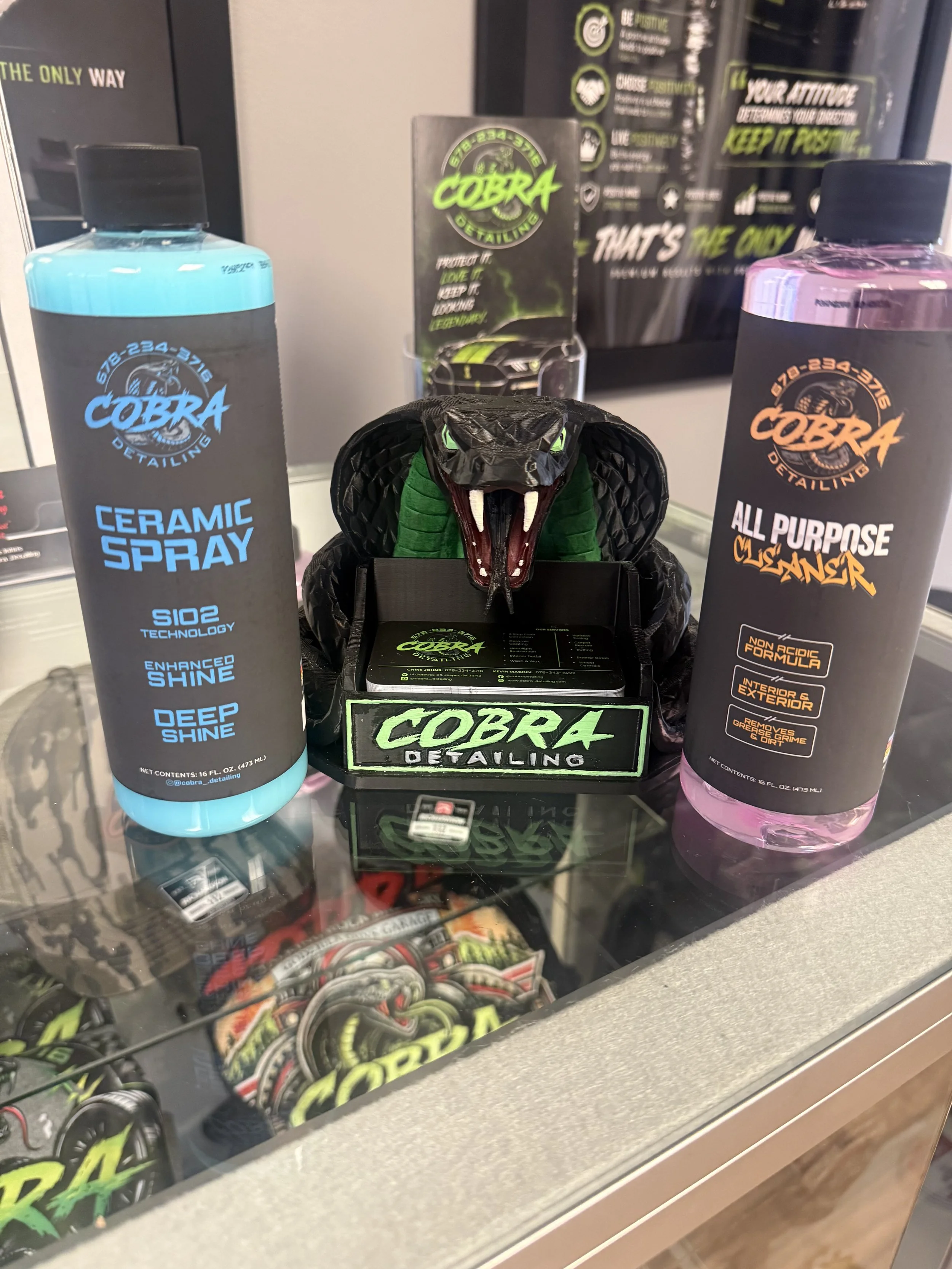 Display case featuring Cobra Detailing automotive products, including ceramic spray and all-purpose degreaser.