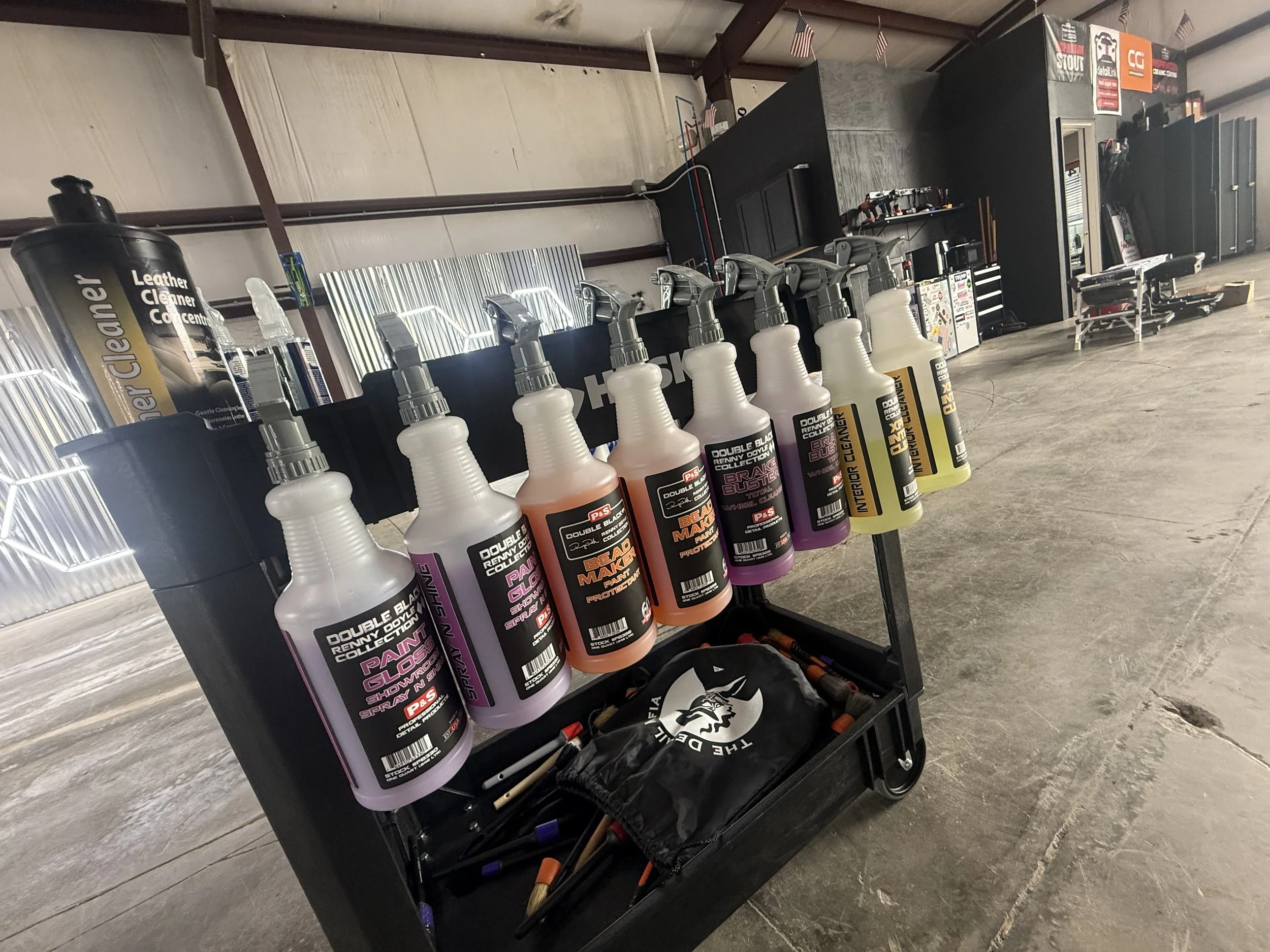 A black rolling cart holding bottles of car detailing sprays.