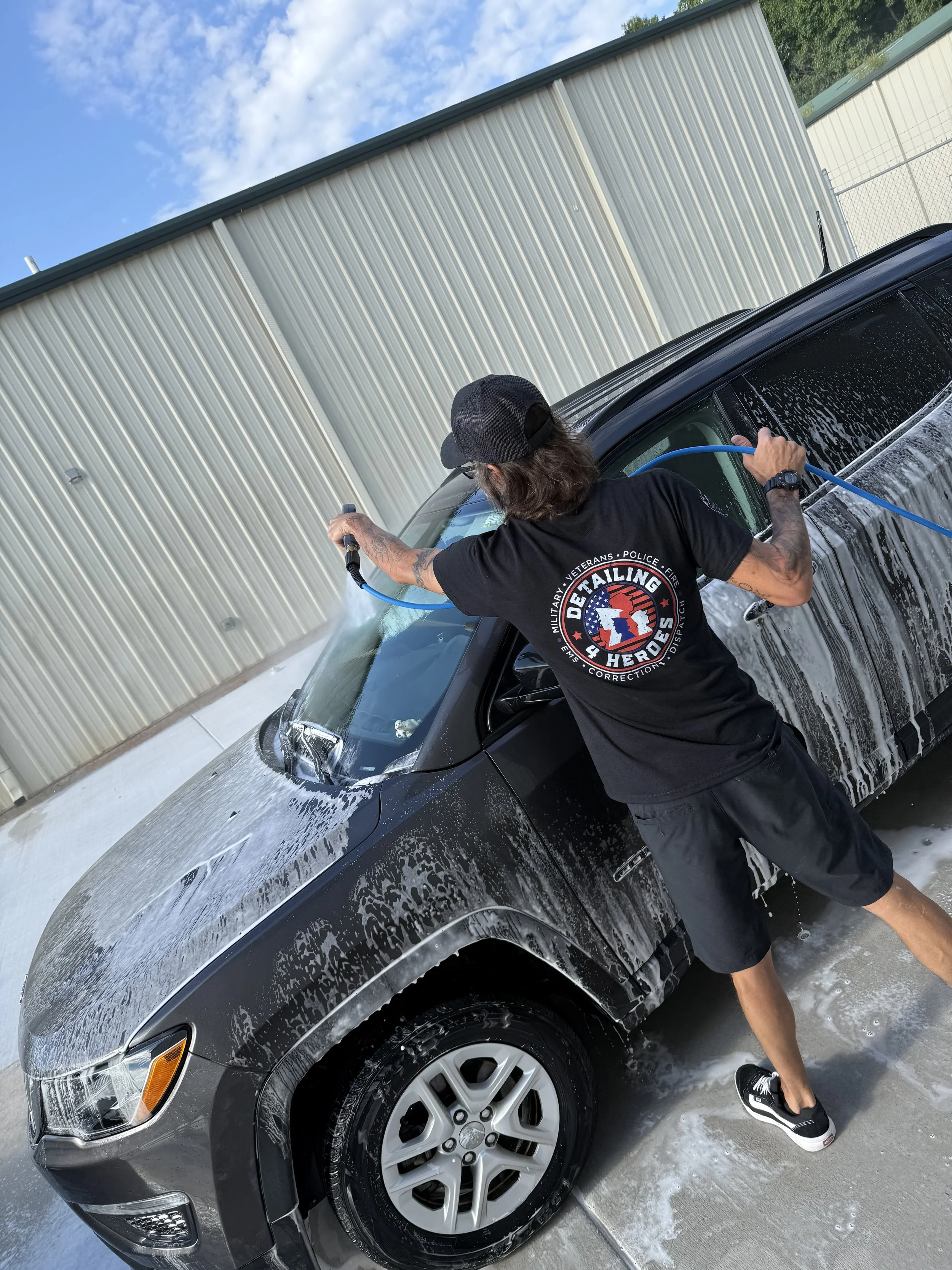 A person washing and detailing a black car .