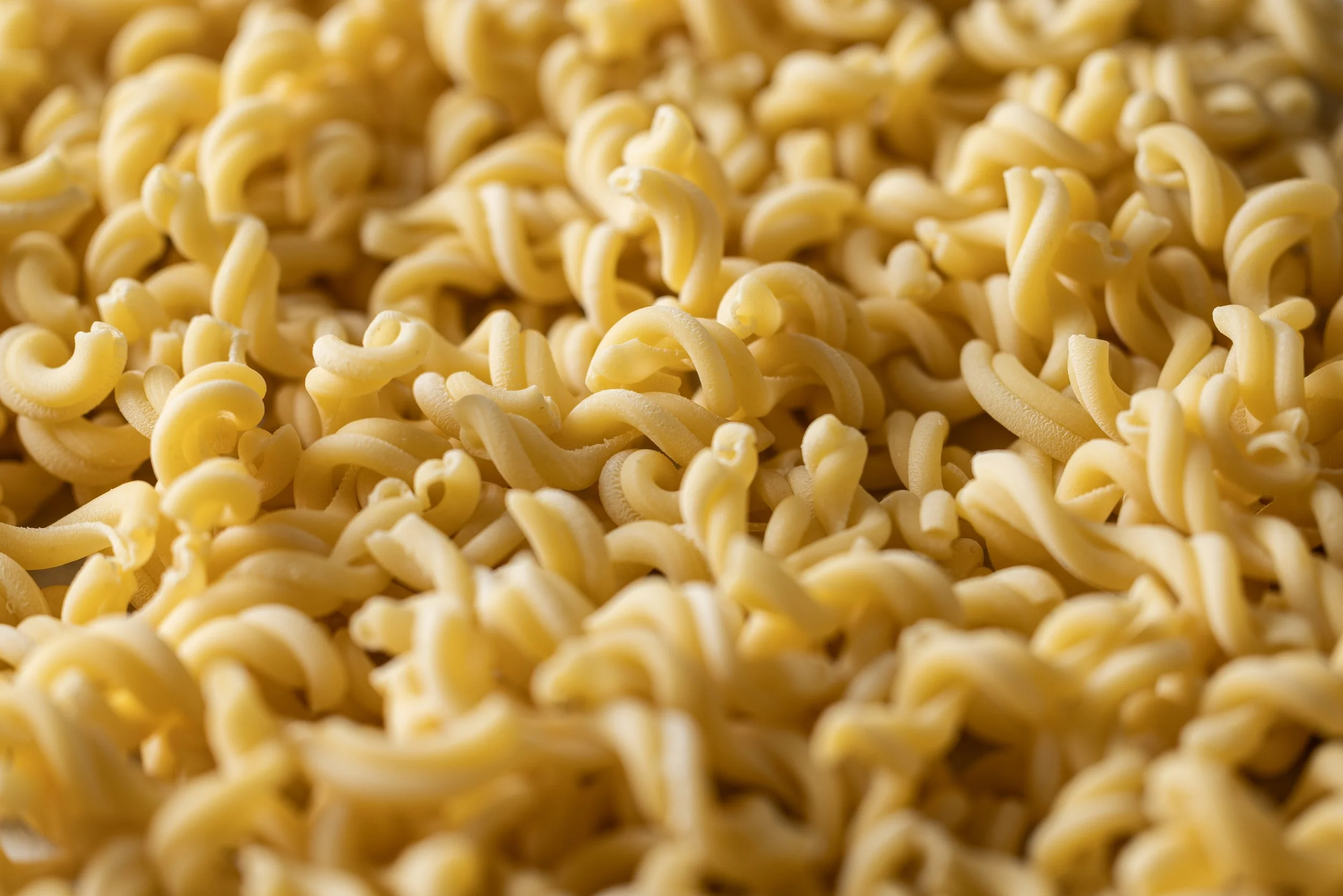 Close-up of uncooked fusilli pasta with a yellowish color.