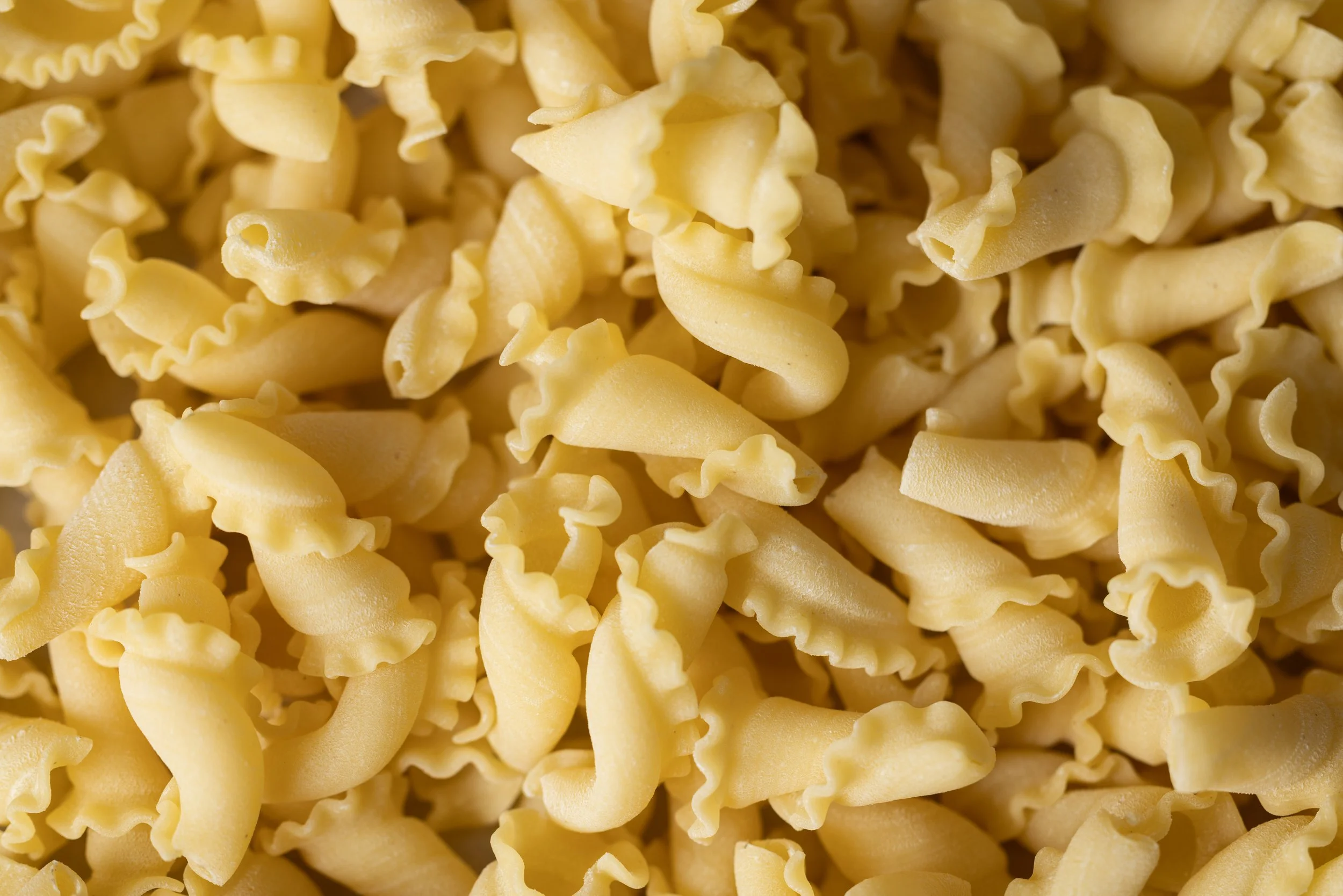 Close-up of uncooked yellow pasta with curly and twisted shapes.