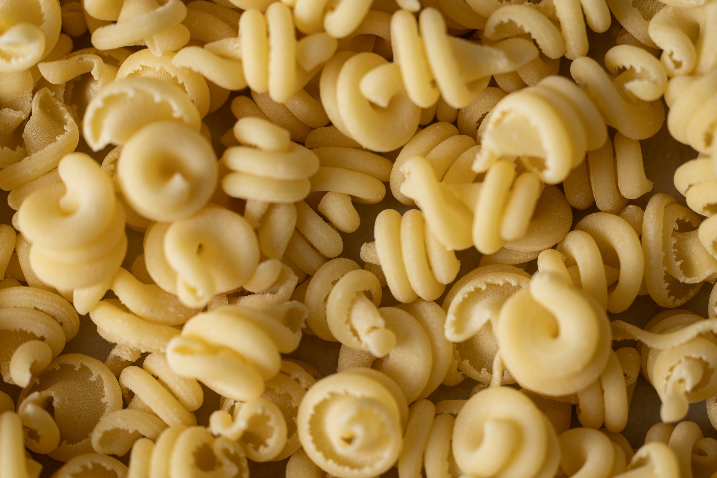 Close-up of uncooked rotini pasta, showing the corkscrew shape and pale yellow color.