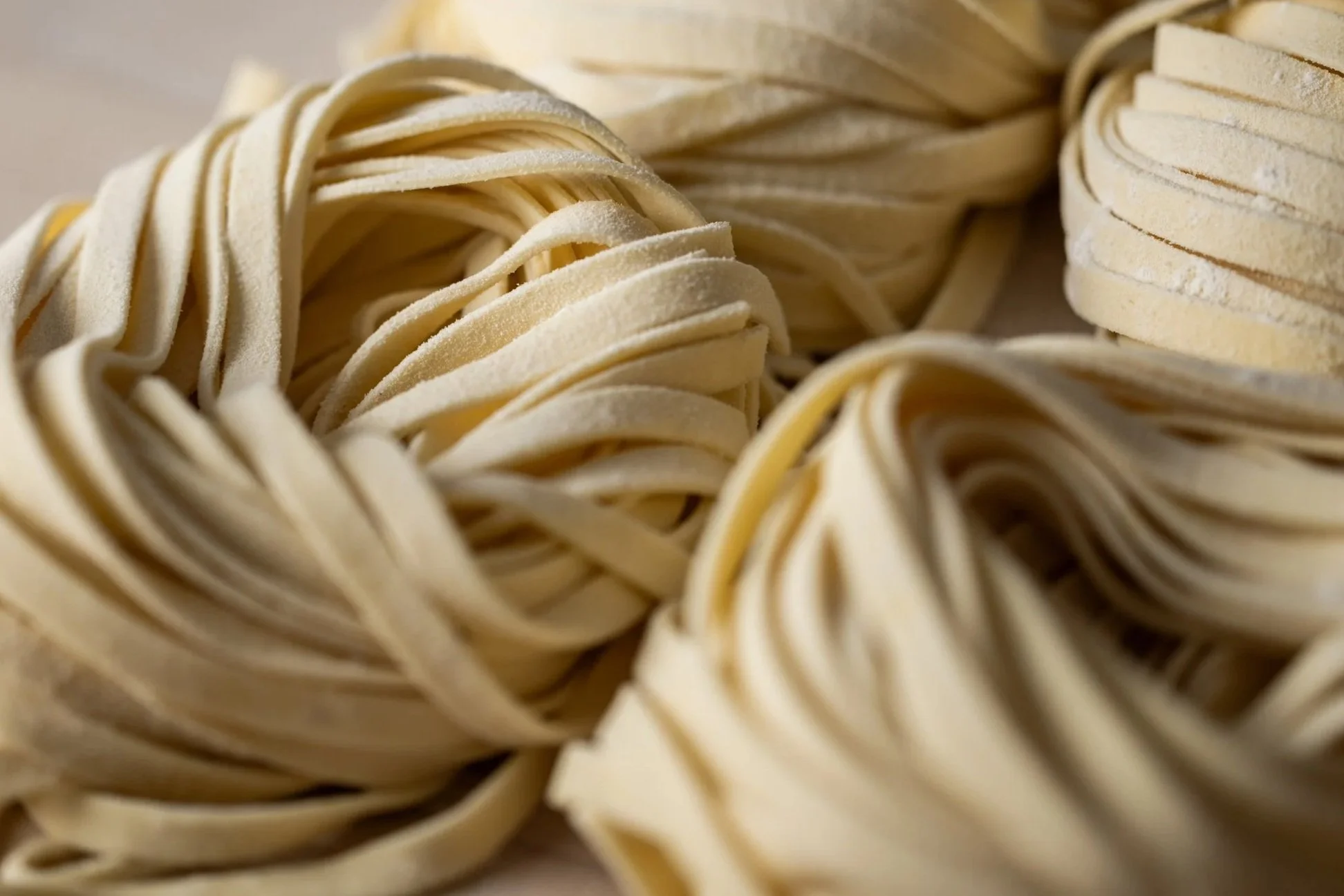 Close-up of uncooked, flat pasta noodles arranged in a nest shape.