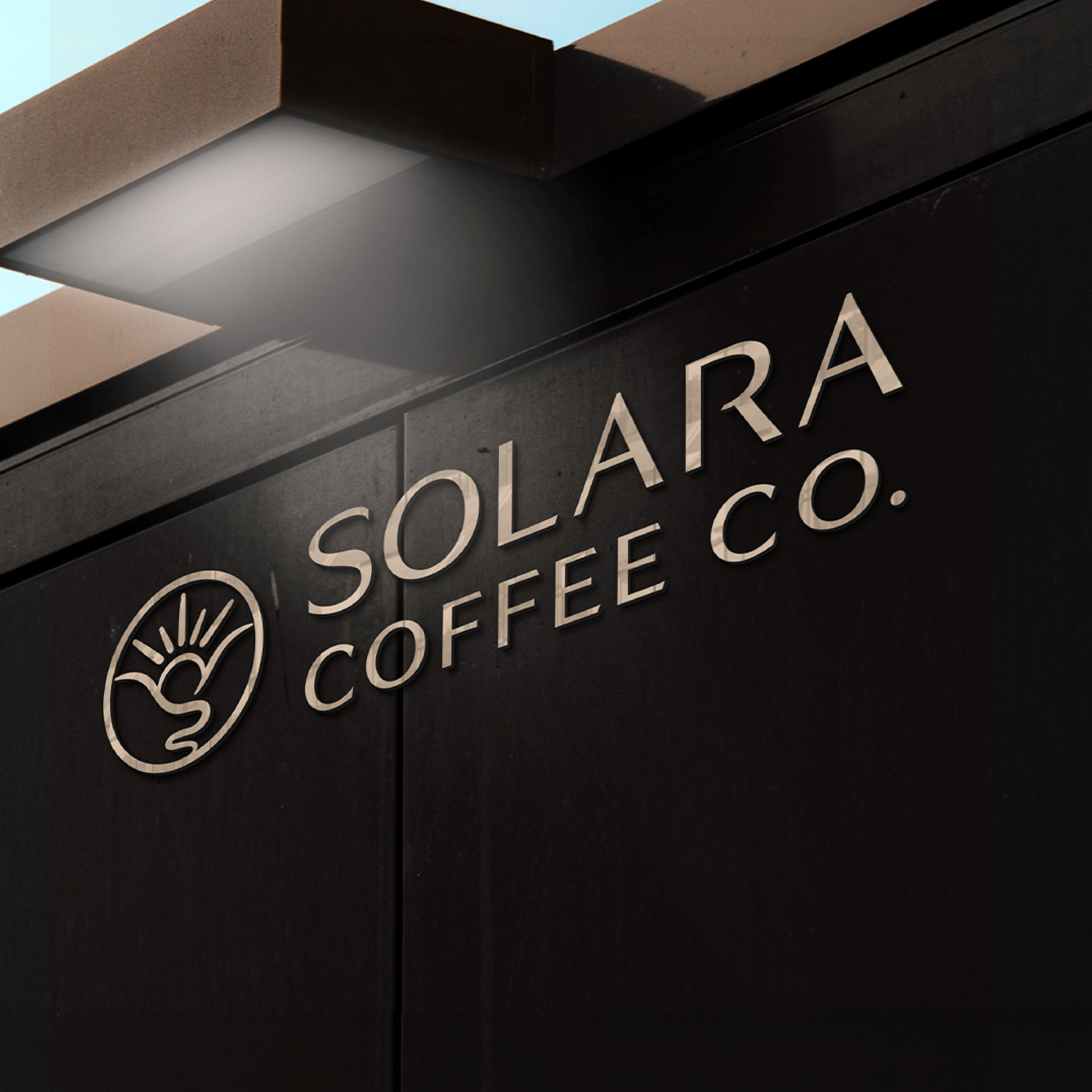 Close-up of a black sign with white lettering that reads 'Solara Coffee Co.' and a circular logo featuring a stylized sun and mountain