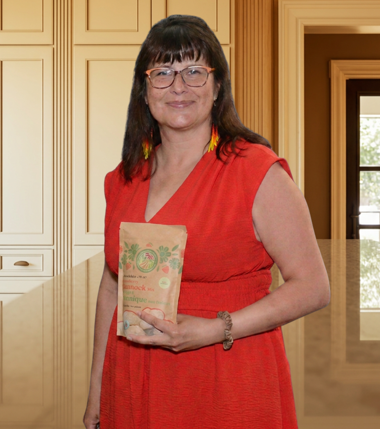 CEO/Founder, Felicia Dewar wearing a red dress and holding a package of strawberry bannock mix