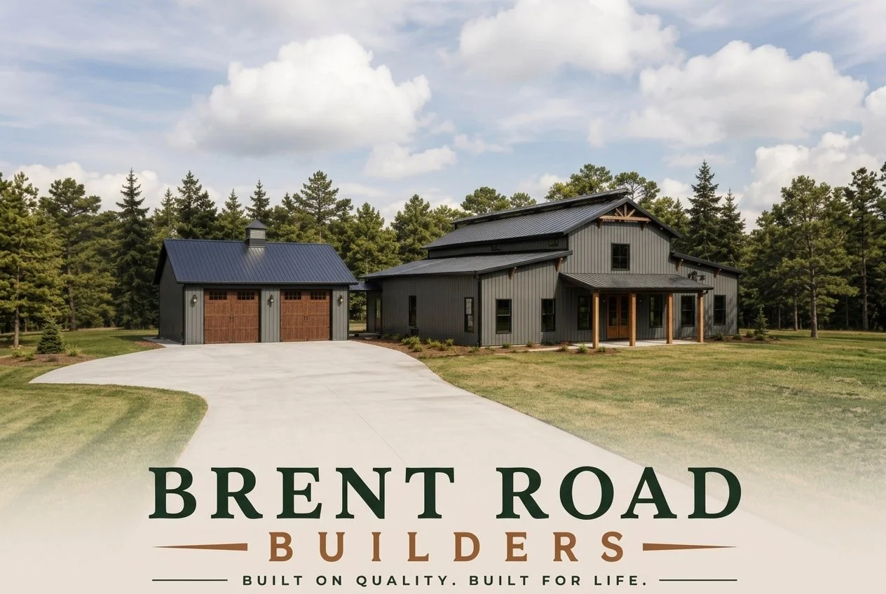 Photo of a modern black house with a metal roof, multiple sections, front porch, and a separate garage nearby, surrounded by green lawn and tall trees under a partly cloudy sky.