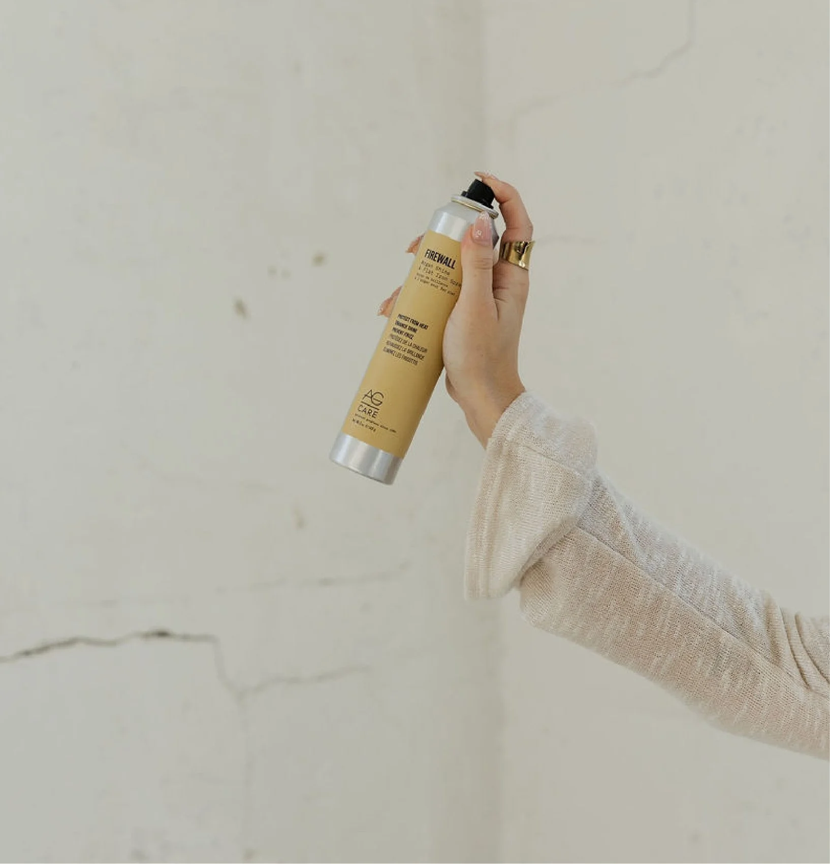 Person holding a spray bottle labeled 'FRESHWALL' against a plain, slightly textured wall.