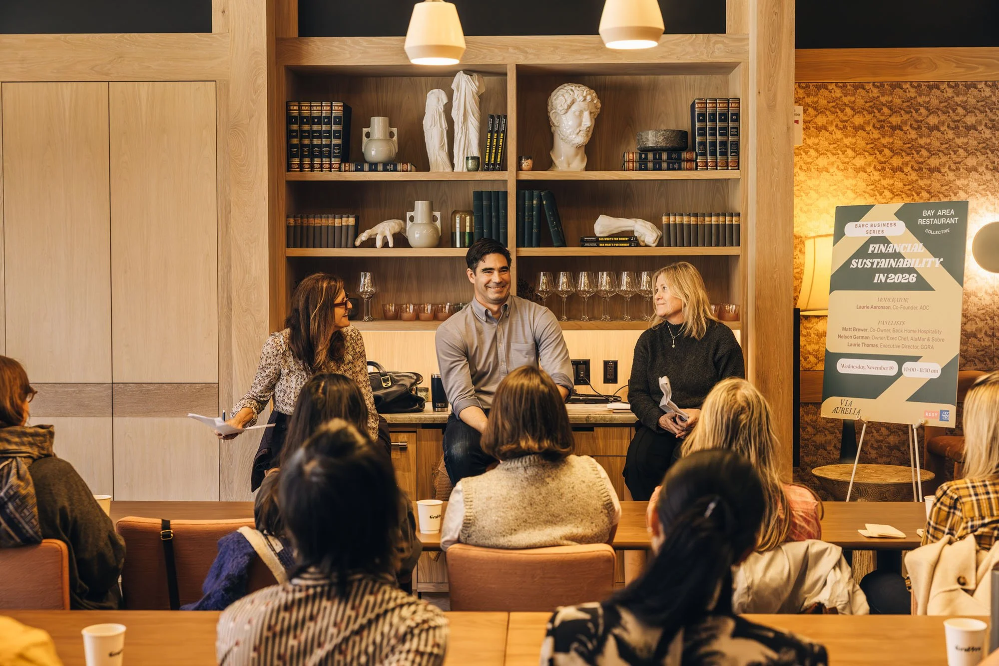 Three people speaking in front of a group at Via Aurelia at a BARC event