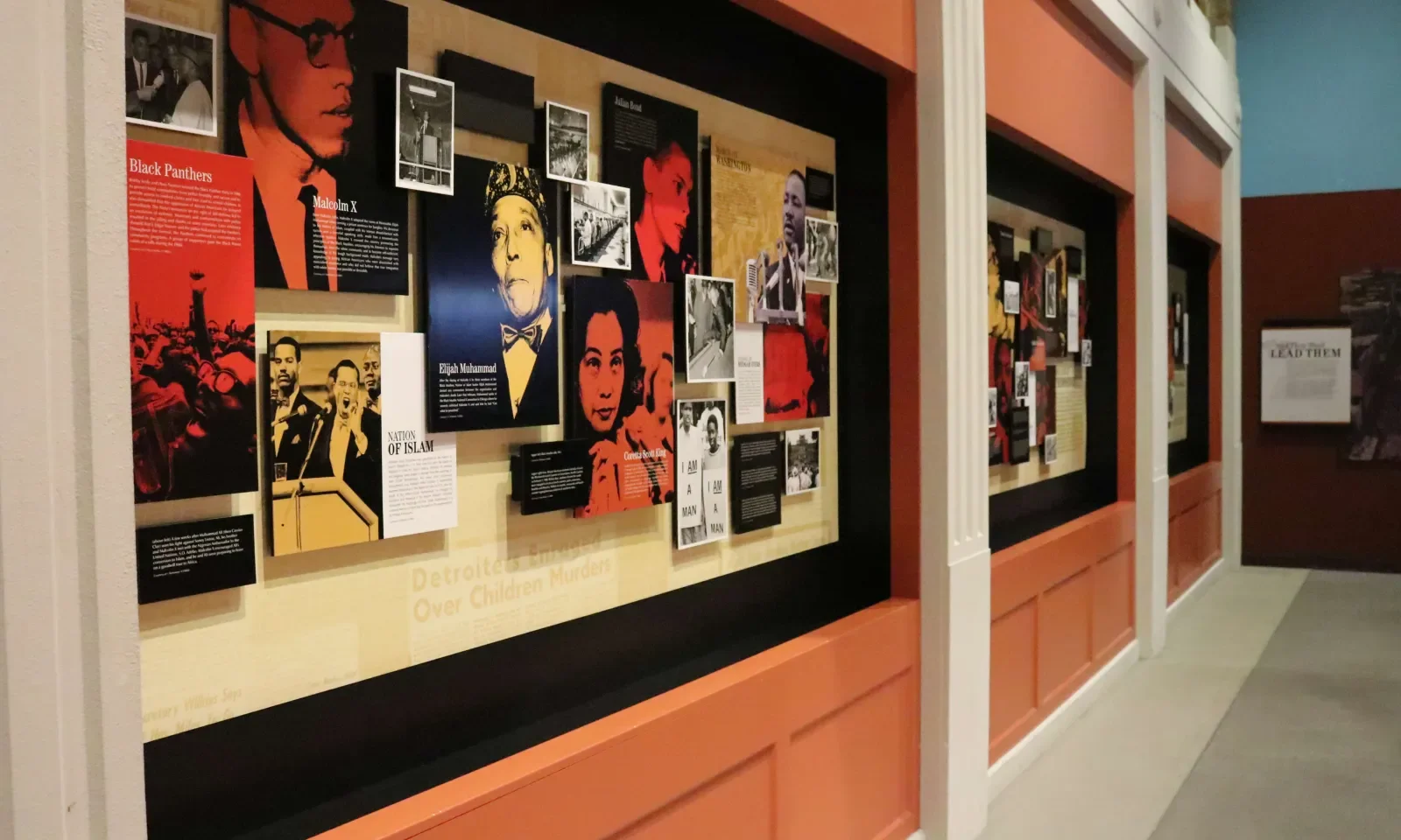 The And Still We Rise display at the Charles H. Wright Museum with portraits and information panels about prominent figures and historical events, including Malcolm X and Elijah Muhammad.