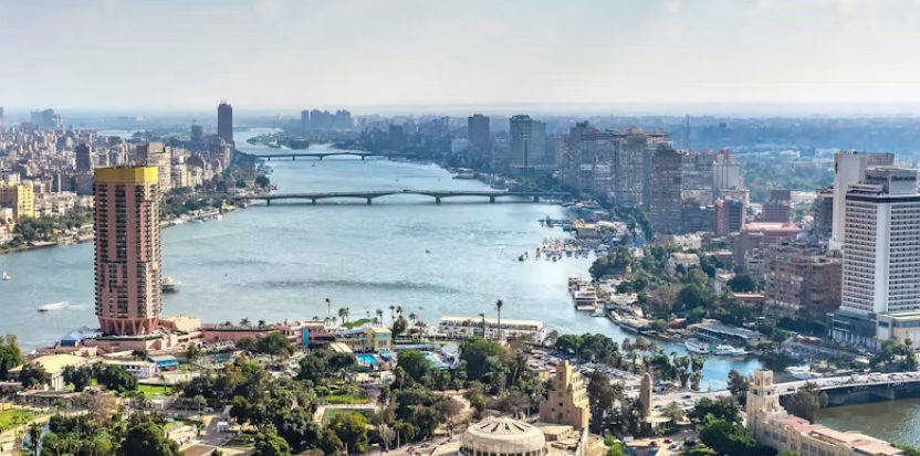 Aerial view of the Nile River flowing through Cairo, Egypt, surrounded by dense urban development along the riverbanks.