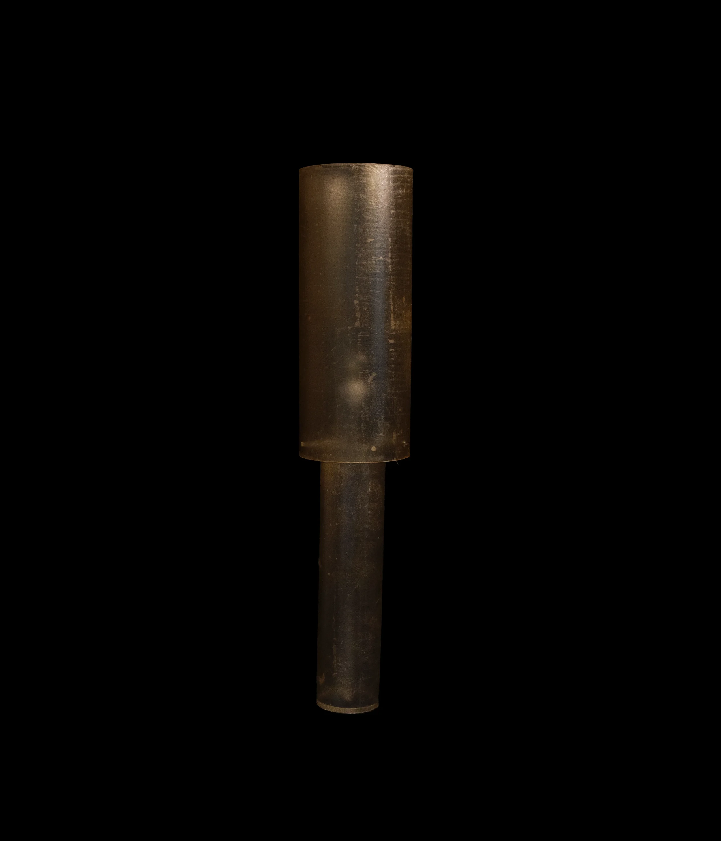 A cylindrical metal object with a rusty appearance, placed vertically against a dark background.