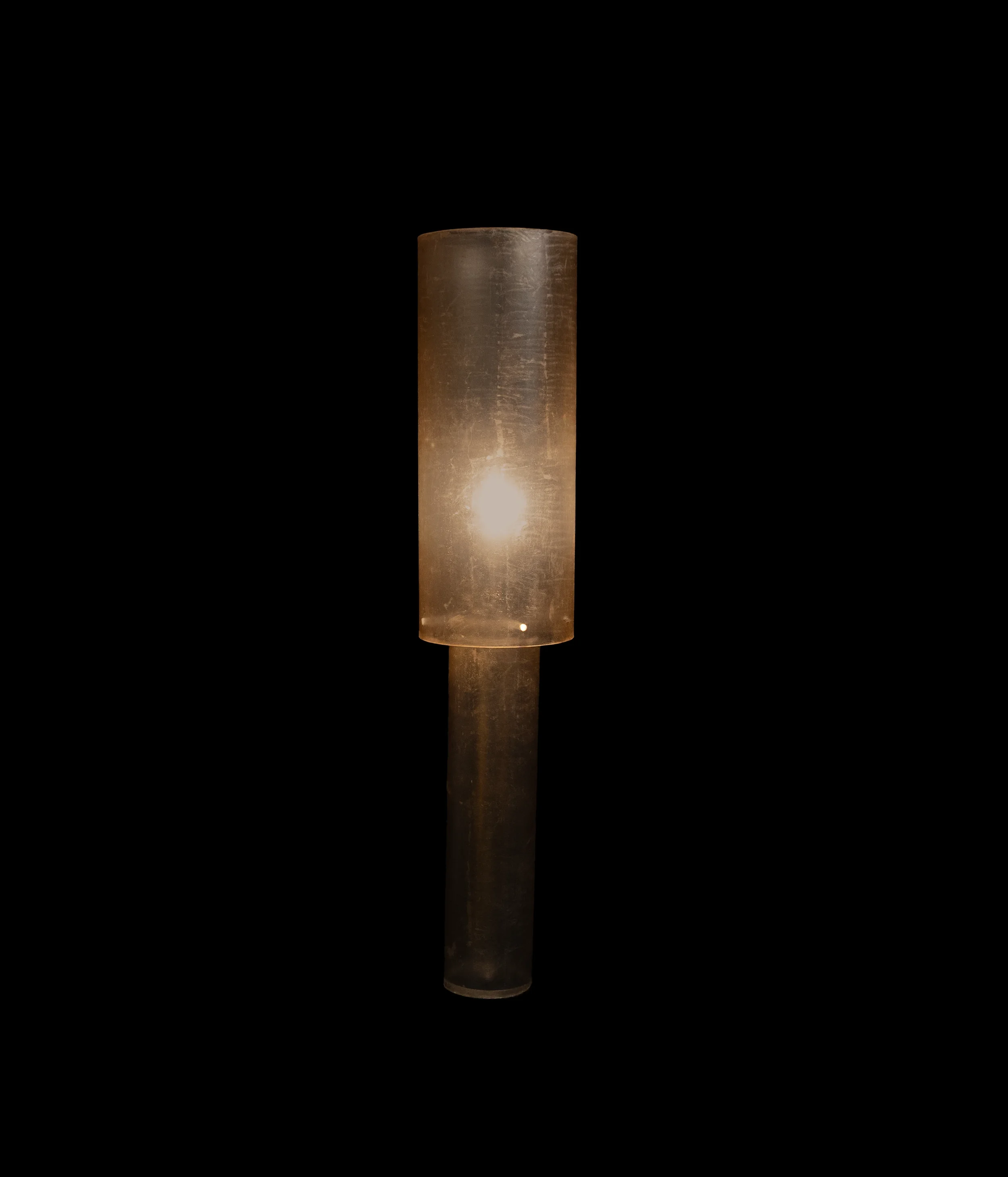 Soft atmospheric diffusion emerging from a tall leather-wrapped monolithic lighting fixture.
