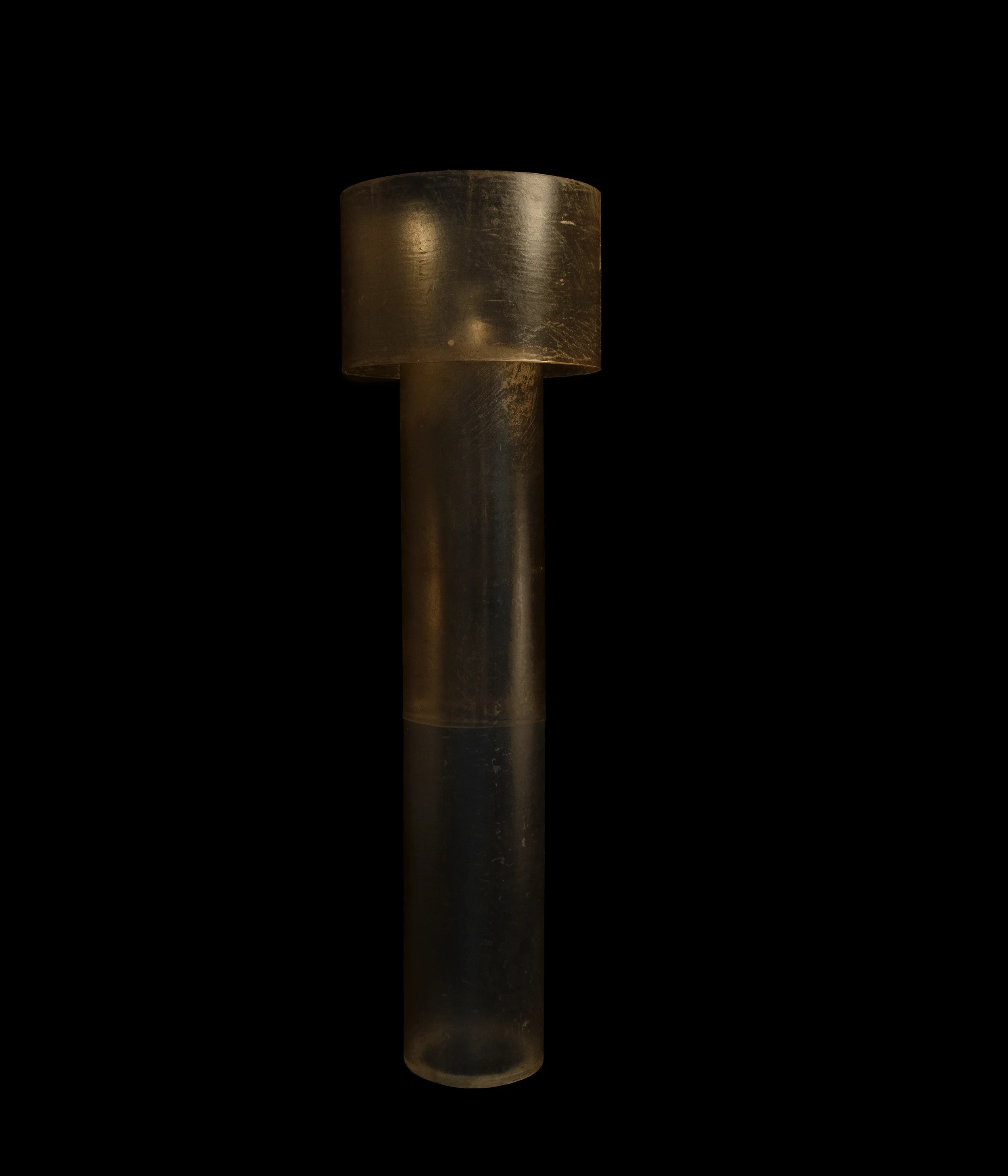 Tall brooding monolithic floor lamp in dark hand-stitched leather, standing as a collectible art object in a dark interior.