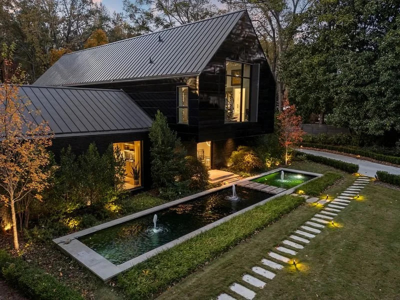 Modern black home with landscaped courtyard and reflecting pool