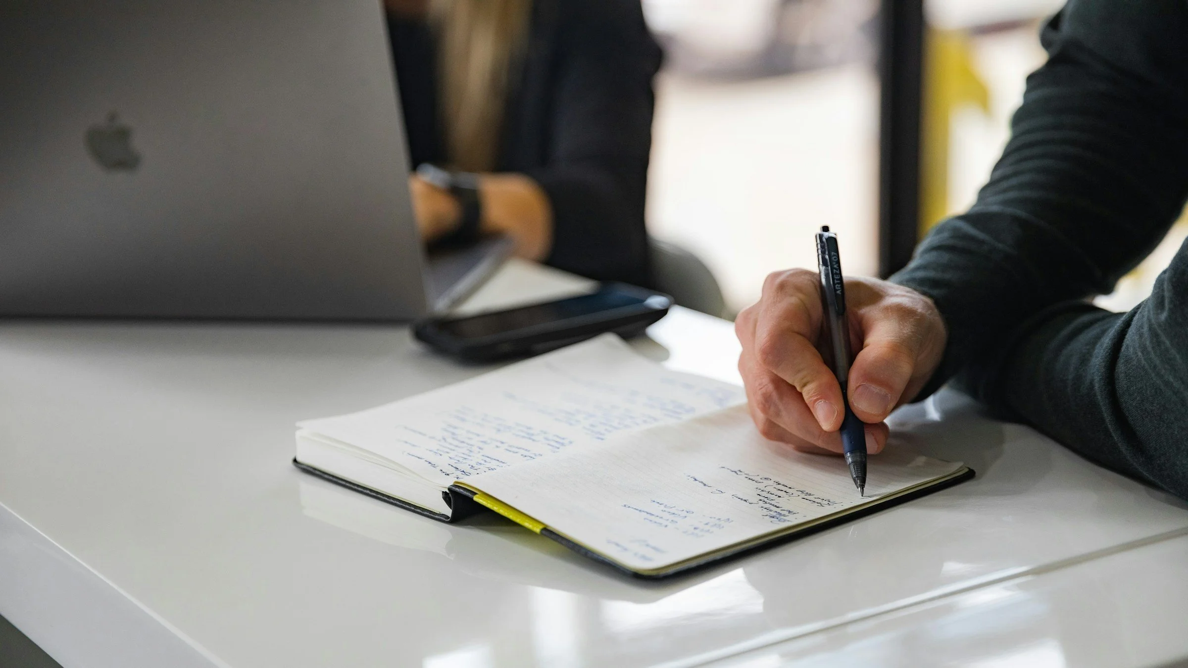 Person taking notes at a desk during research.